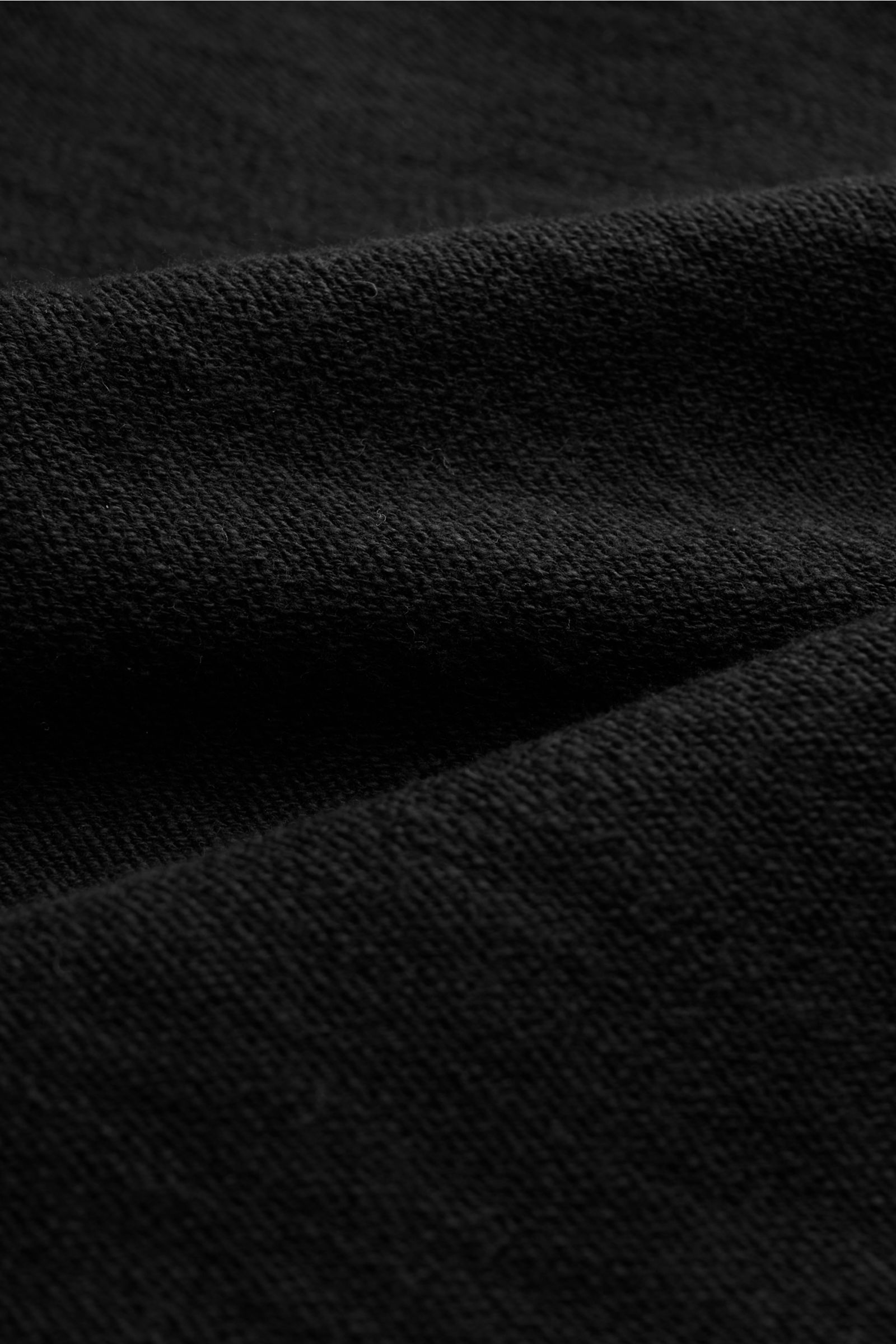 Close-up front view of the Stone Island Half-zip jumper black showing its medium-fine purl stitch knit texture. Knit with a twist: The sporty half-zip jumper by STONE ISLAND in a modern purl stitch is an ideal leisure companion and offers versatile stylin