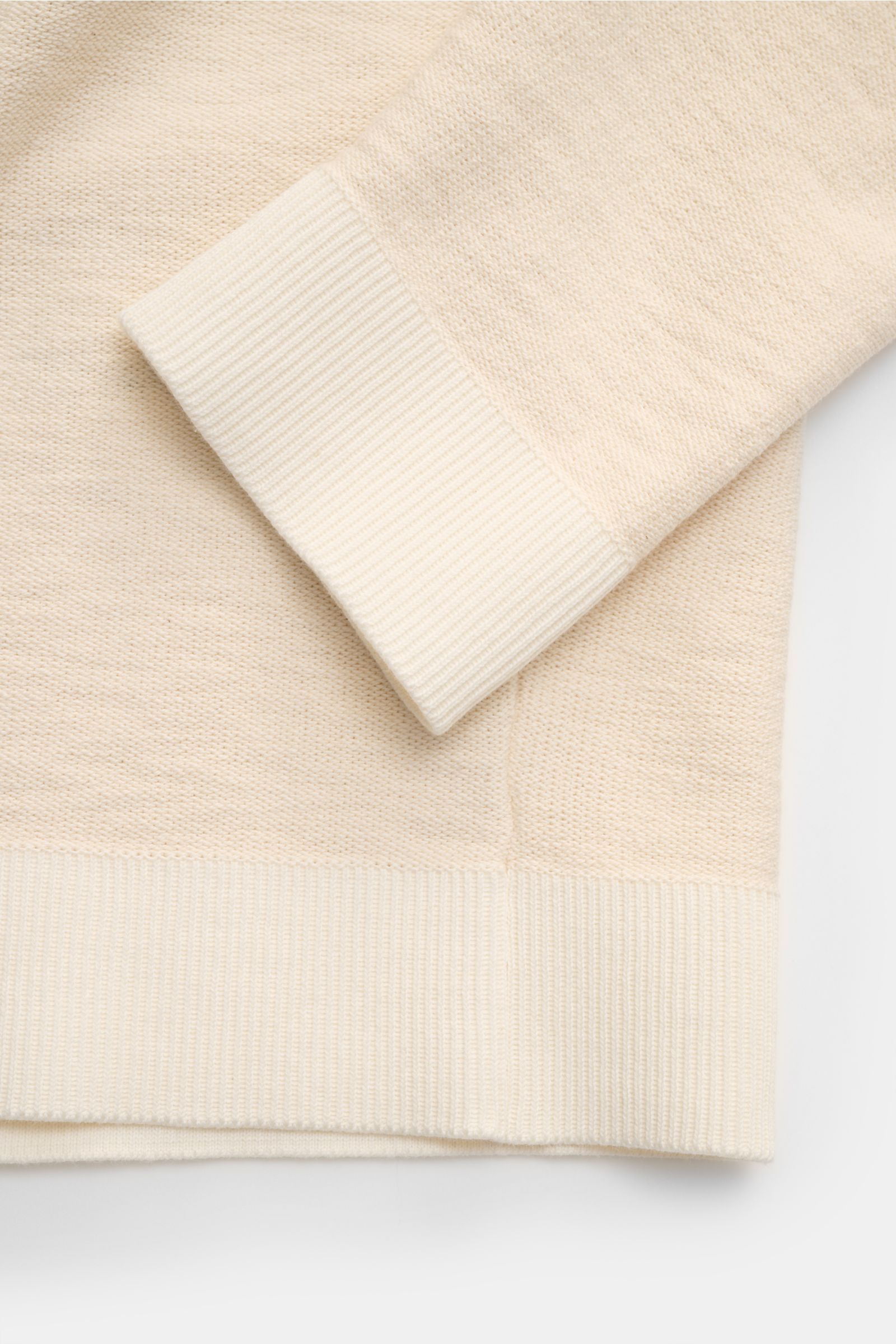 Close-up of the sleeve and hem of the Stone Island Half-zip jumper cream, showing medium-fine purl stitch knit with ribbed bands, photographed from above.

Description: 
Knit with a twist: The sporty half-zip jumper by STONE ISLAND in a modern purl sti