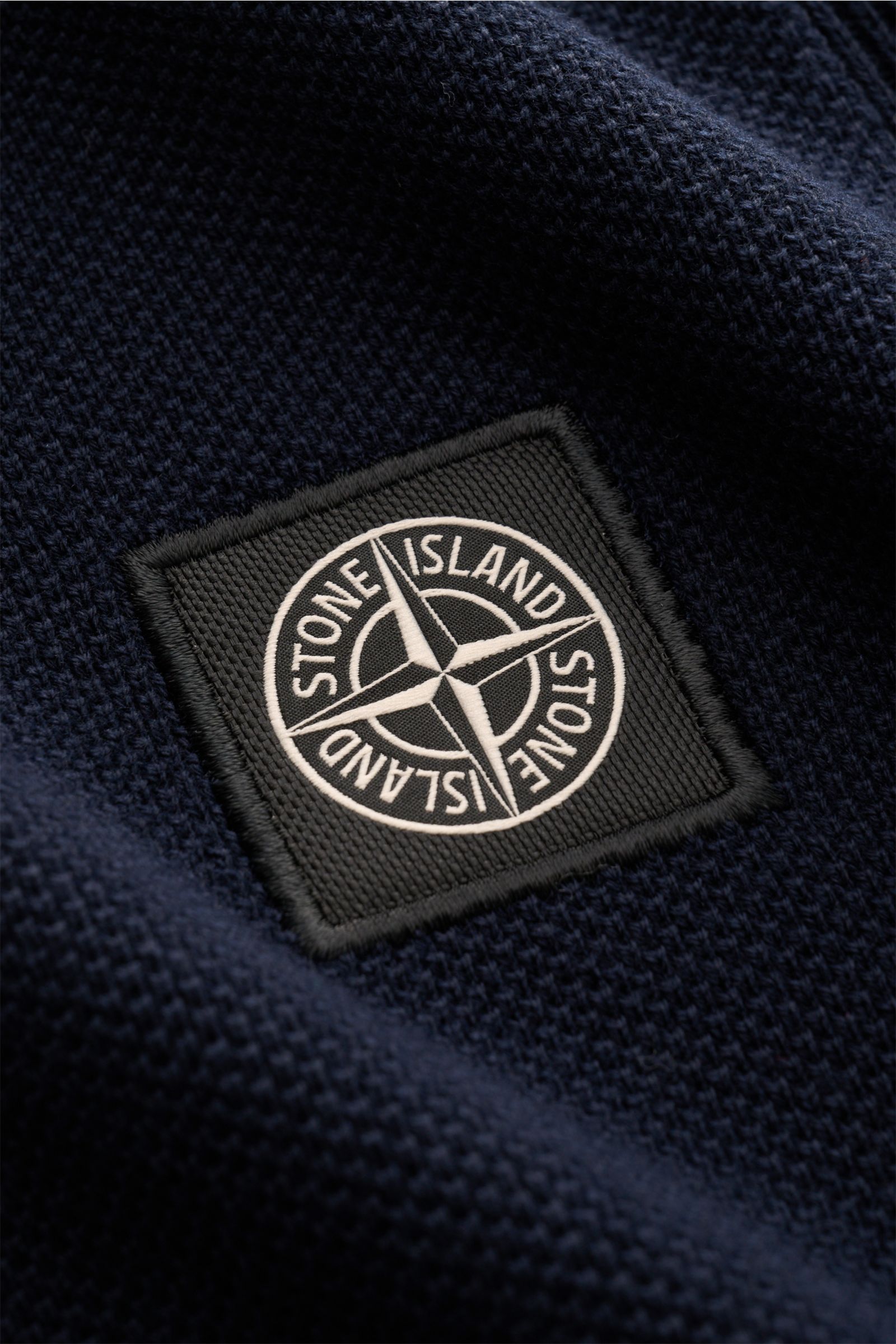Nahaufnahme des Stone Island Kurzarm-Strickpolo navy mit feinem Piqué-Mix, Polokragen und gesticktem Weblabel, textile Struktur sichtbar.