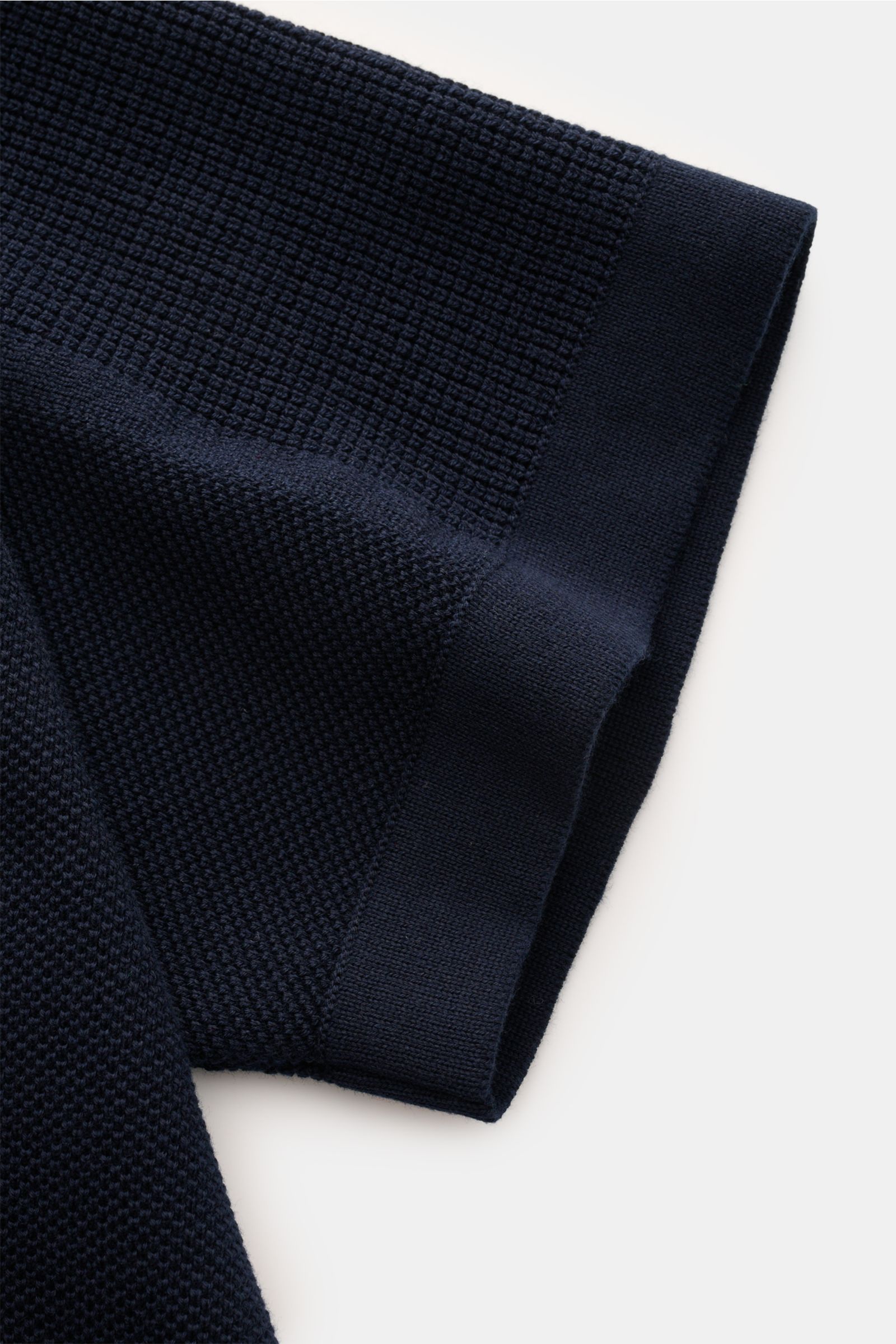 Nahaufnahme des Ärmels vom Stone Island Kurzarm-Strickpolo navy, fotografiert von oben, mit feinem Piqué-Mix, Polokragen, regular fit, reiner Baumwolle und seitlichen Saumschlitzen.