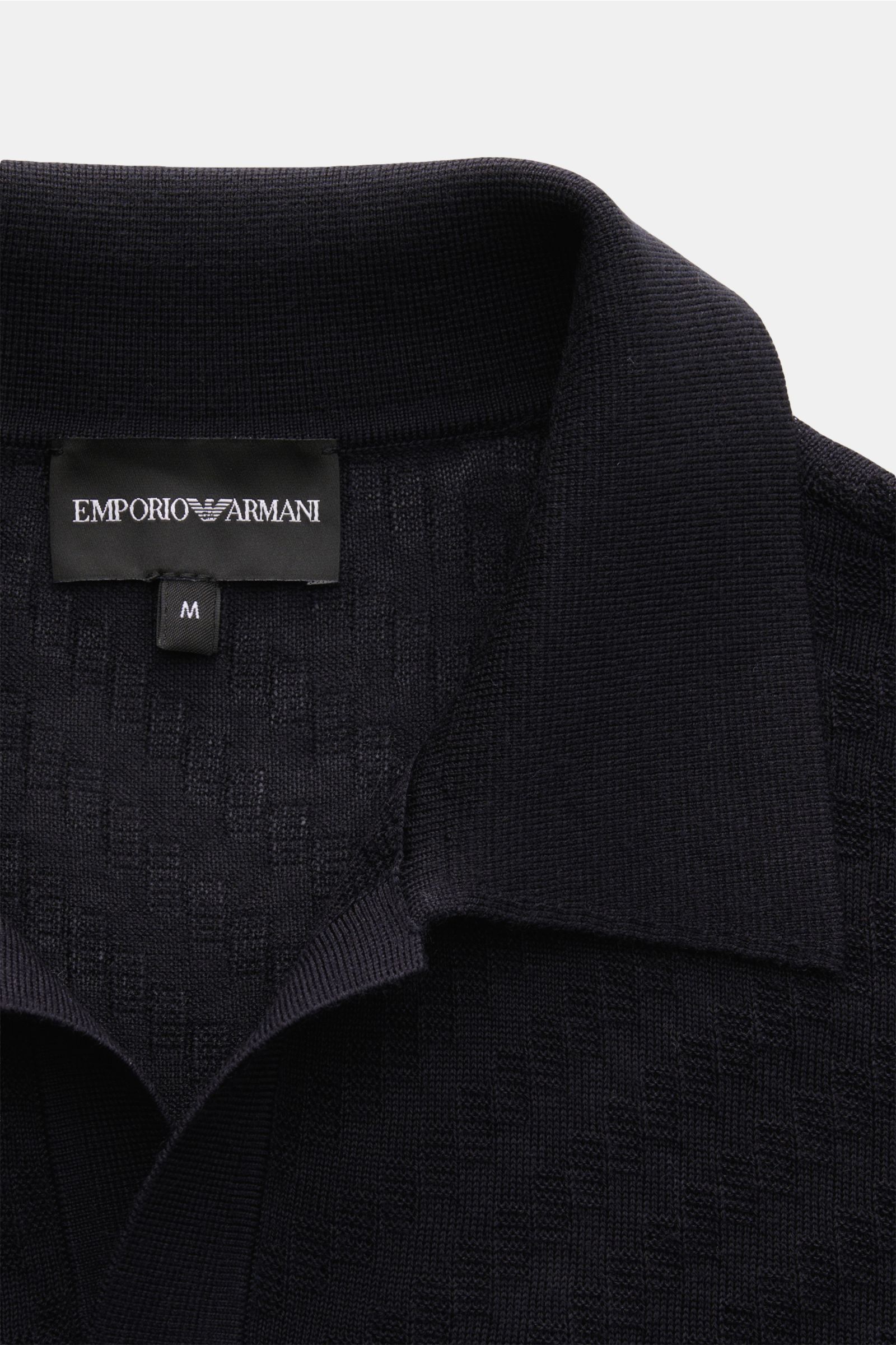 Emporio Armani Kurzarm-Strickpolo navy mit feinem Strukturstrick, offenem Kragen, komfortablen Rippbündchen, Slim Fit, fotografiert aus Nahaufnahme von oben.