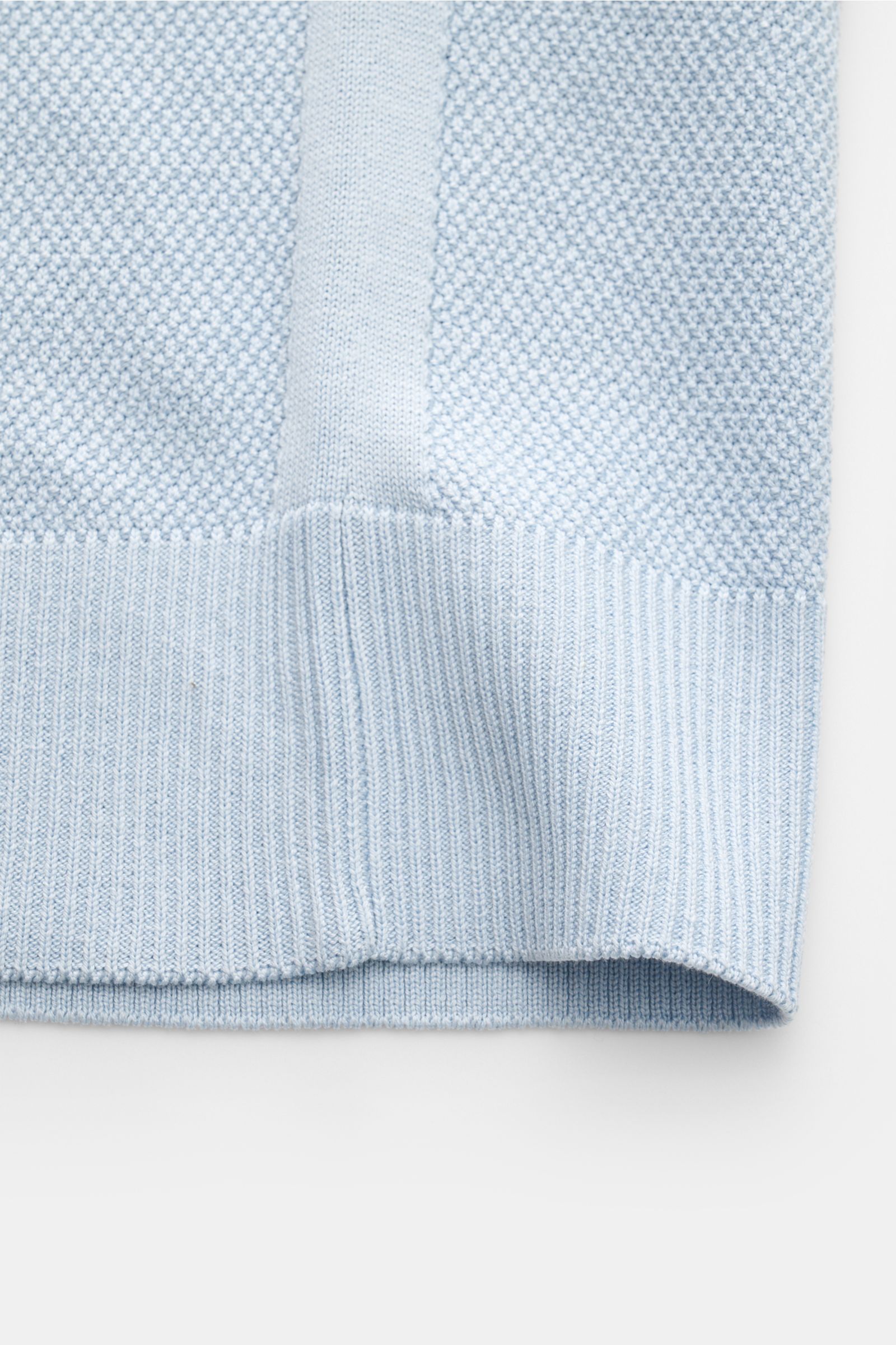 Nahaufnahme des unteren Saums vom Belstaff Kurzarm-Strickpolo 'Coast' hellblau aus Seide-Baumwoll-Mix mit feinem Strukturstrick und Rippbündchen.