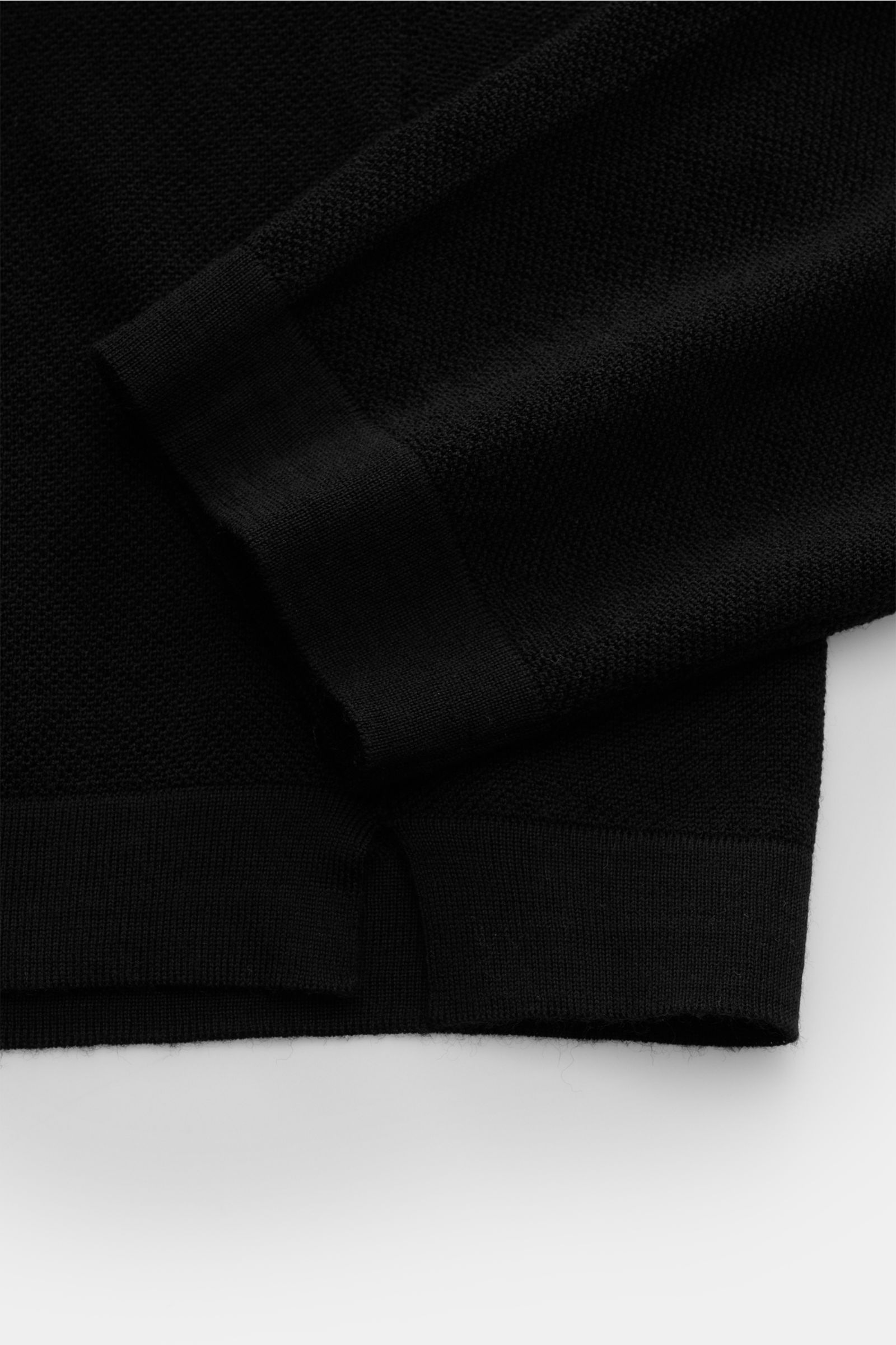 Close-up side view of the cuff and hem of the 04651/ A trip in a bag Knit polo 'Johnny' black, made of fine knit pure wool with ribbed bands.

Stylish comfort: This knit polo by 04651/ A TRIP IN A BAG in comfortable pure wool material is a versatile fa