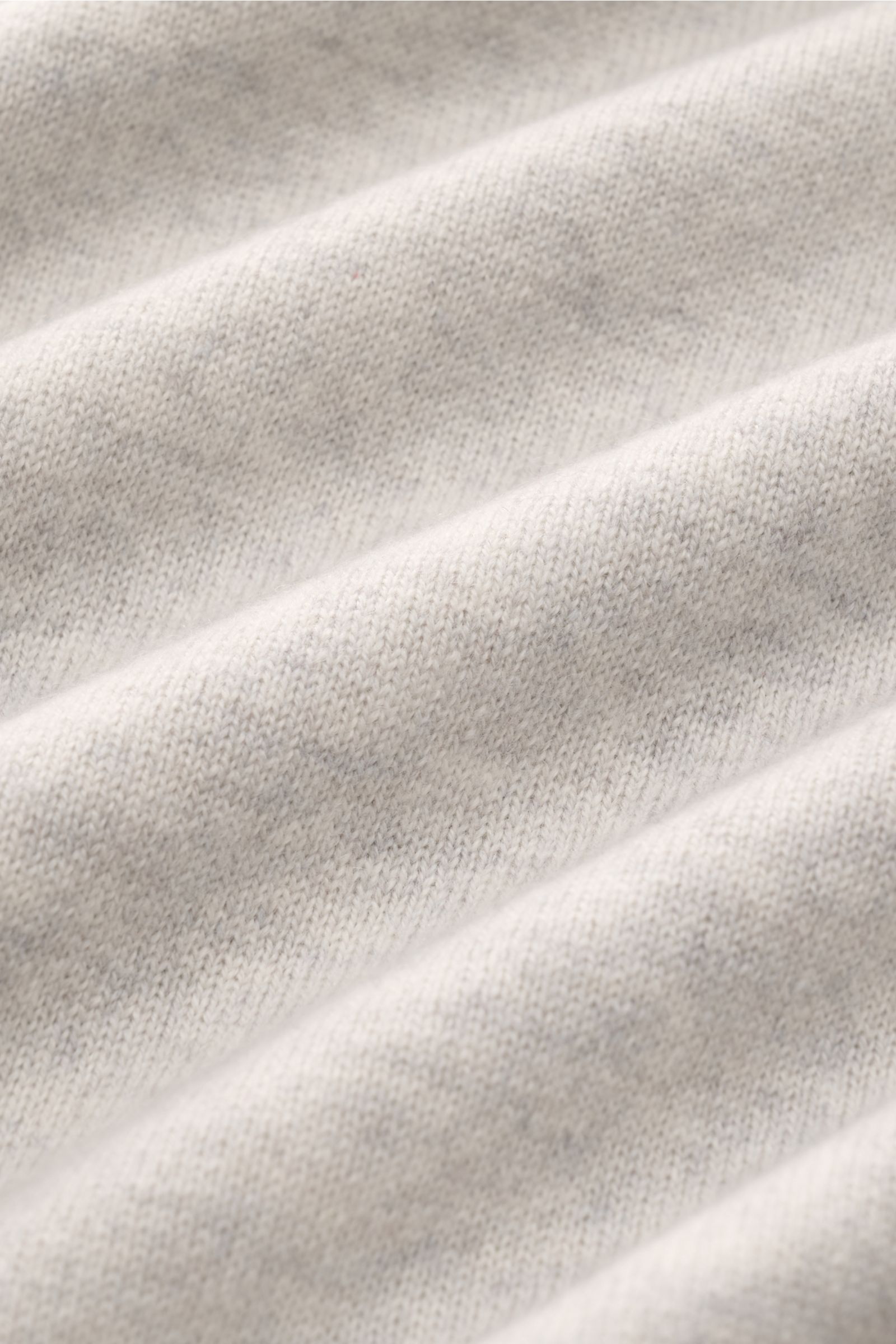 Close-up view of the finely knitted, soft fabric texture of the Brunello Cucinelli Cashmere Troyer hellgrau meliert in light heather gray. Sportives Freizeit-Essential made in Solomeo: Der Troyer aus reinem Cashmere von BRUNELLO CUCINELLI setzt einen luxu