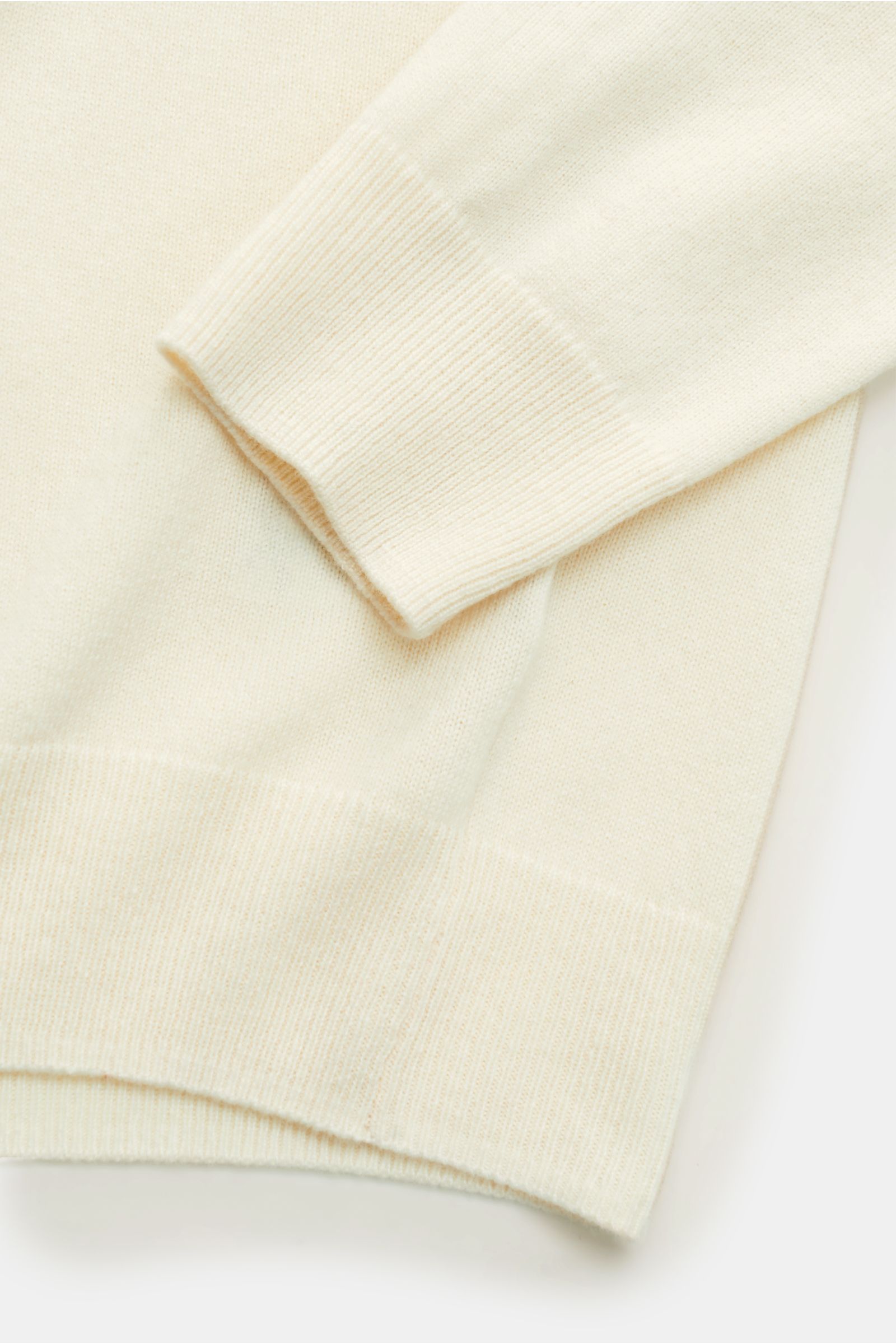 Von oben nah fotografierter von Braun Cashmere Troyer creme mit Slim Fit, feinem Strickbild, Troyerkragen mit Zipper, weichem Griff und flexiblen Rippbündchen.