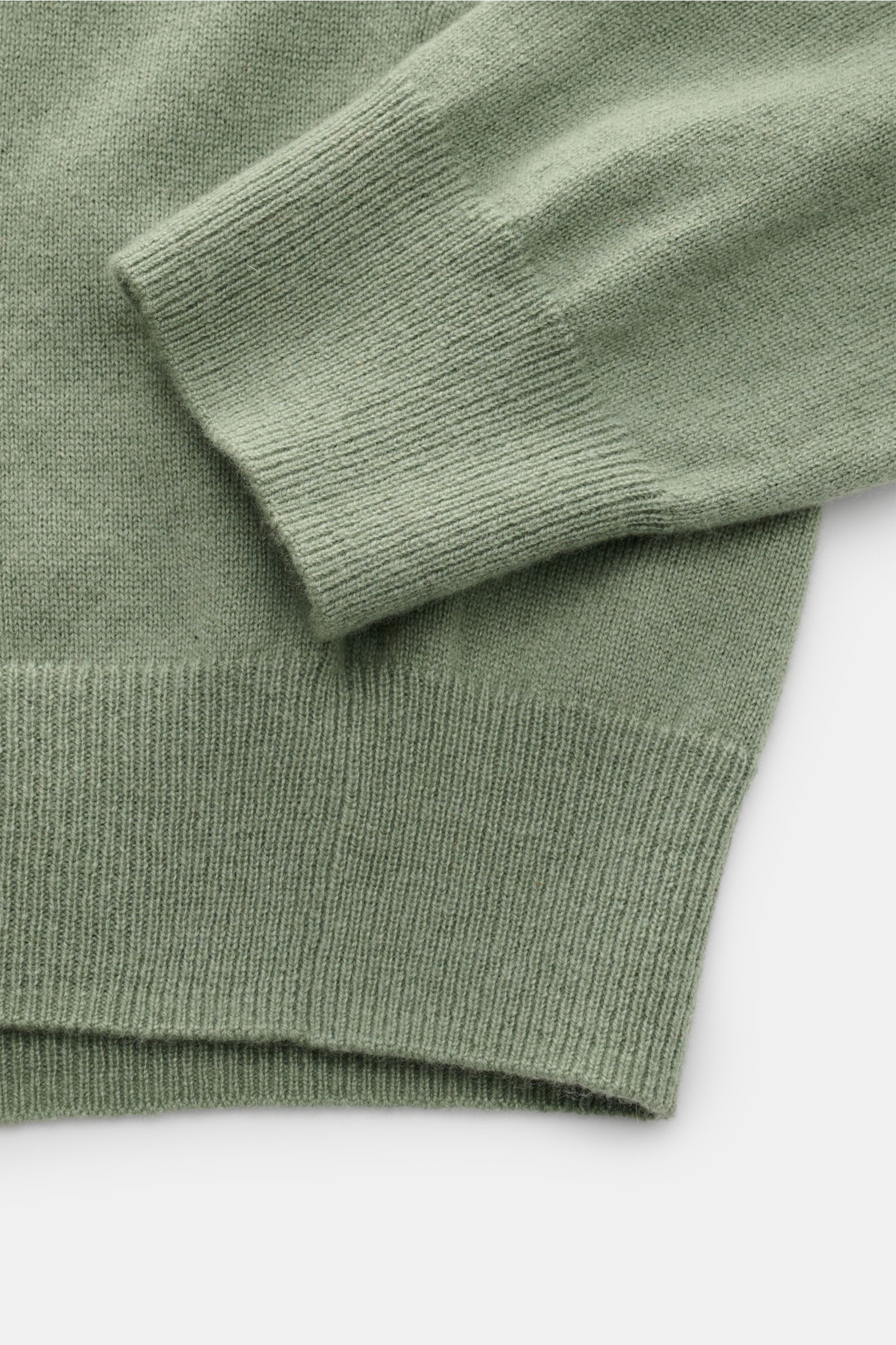 Nahaufnahme des von Braun Cashmere Troyer salbei von unten schräg, zeigt feines Strickbild, reinen Cashmere, Slim Fit, weichen Griff, typischen Troyerkragen mit Zipper und flexible Rippbündchen.
