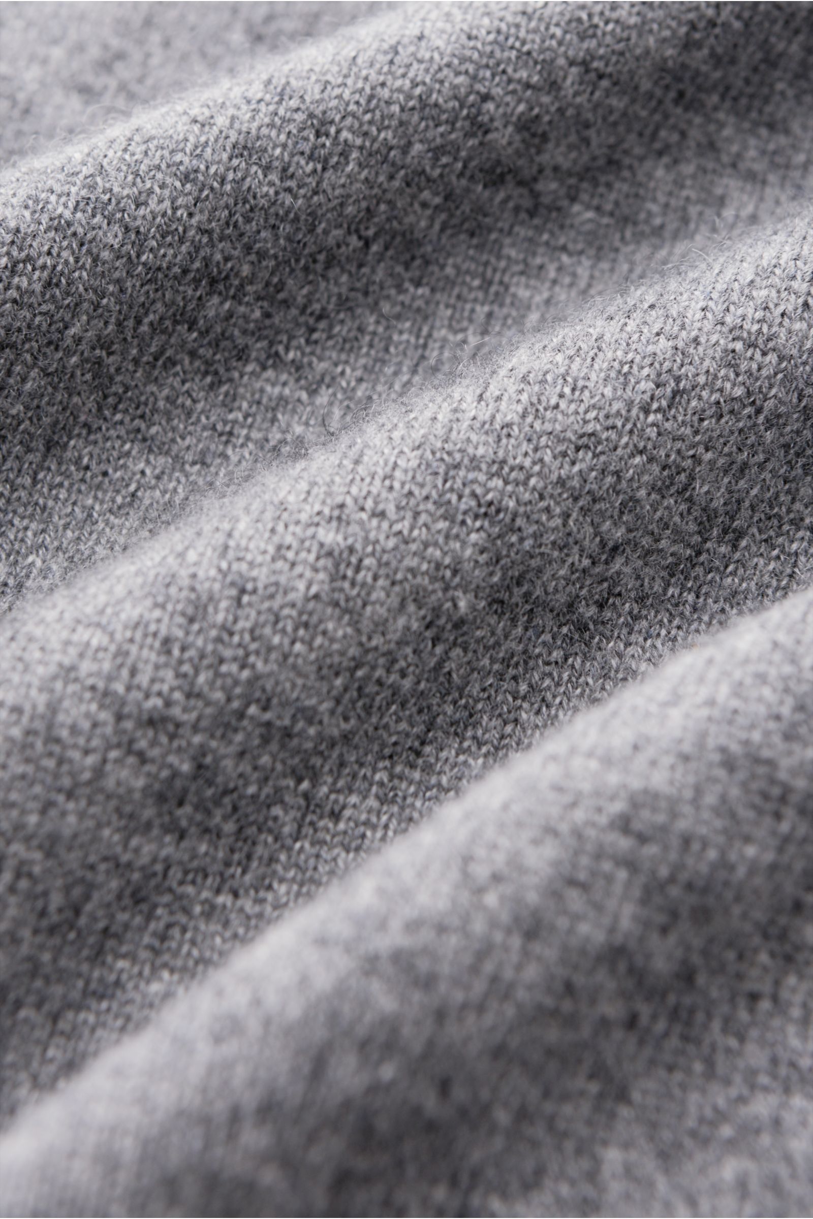 von Braun Cashmere Troyer grau meliert in Nahaufnahme, feines Strickbild, weicher Griff, reiner Cashmere aus Innerer Mongolei, Slim Fit, Troyerkragen mit Zipper, flexible Rippbündchen, zeitloses Design, Perspektive zeigt Detailstruktur des Stoffes.