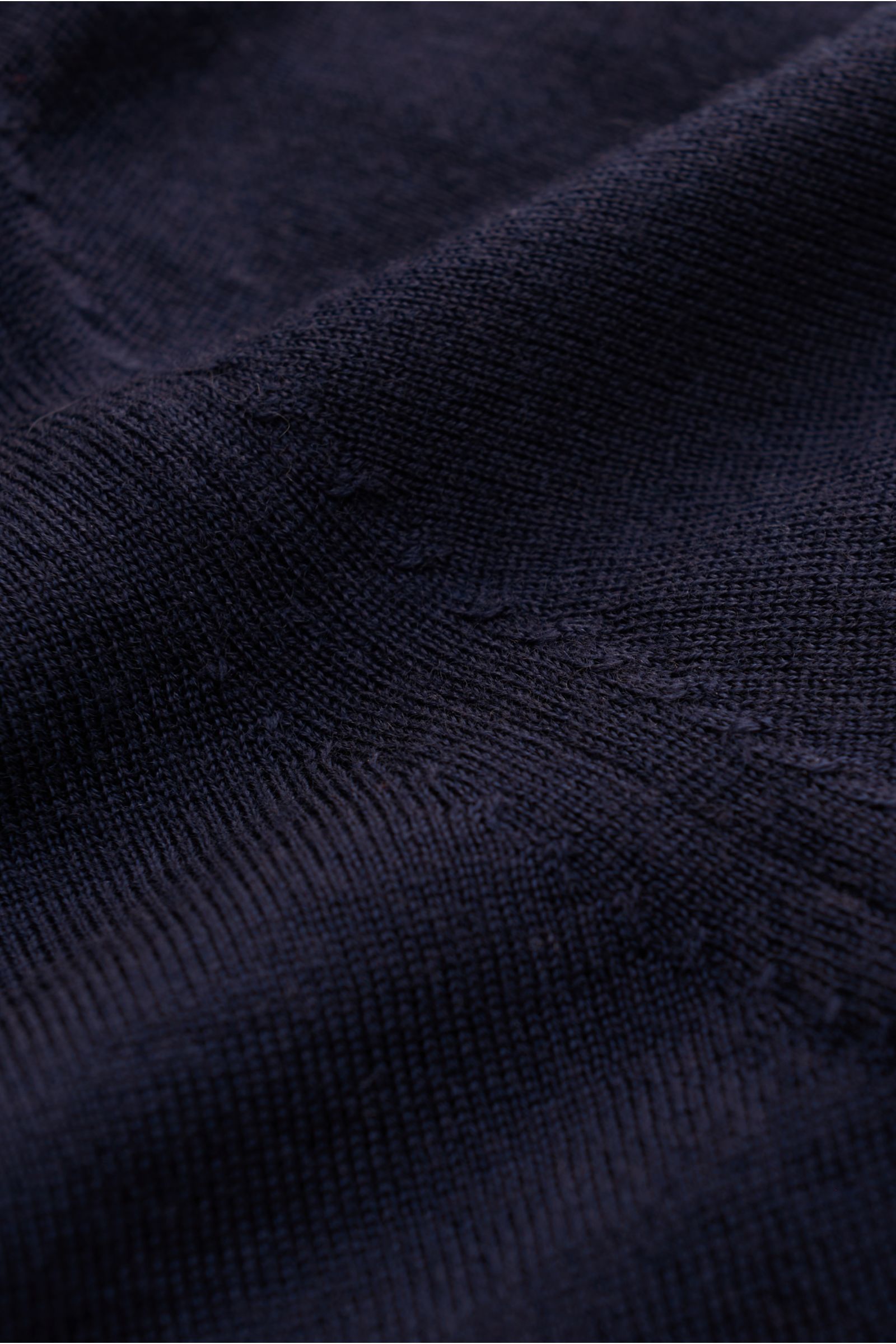 Nahaufnahme des von Braun Merino Feinstrickpolo navy, reine Merinowolle, feines Strickbild, glatte Naht, aus schräger Perspektive.