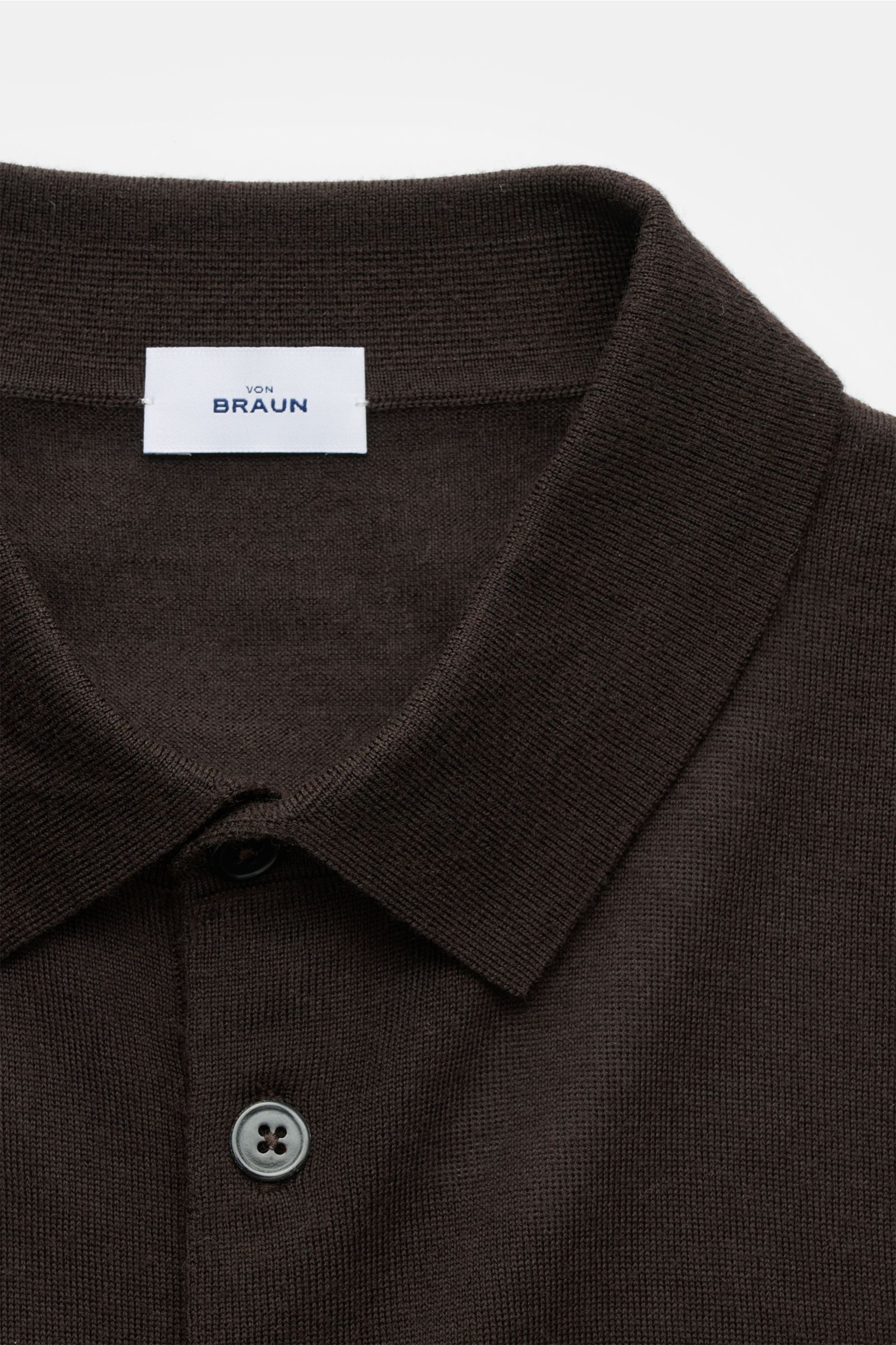 Nahaufnahme des von Braun Merino Feinstrickpolo dunkelbraun von oben, zeigt schmalen Polokragen, glatte Drei-Knopf-Leiste, feines Strickbild aus reiner Merinowolle mit komfortablen Rippbündchen in Slim Fit.