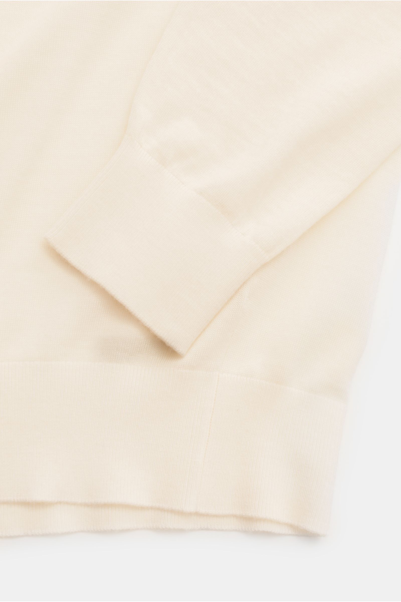 Nahaufnahme des Ärmel- und Bundbereichs vom von Braun Merino Feinstrickpolo creme, Slim Fit, mit glattem, feinem Strickbild und komfortablen Rippbündchen aus reiner Merinowolle.