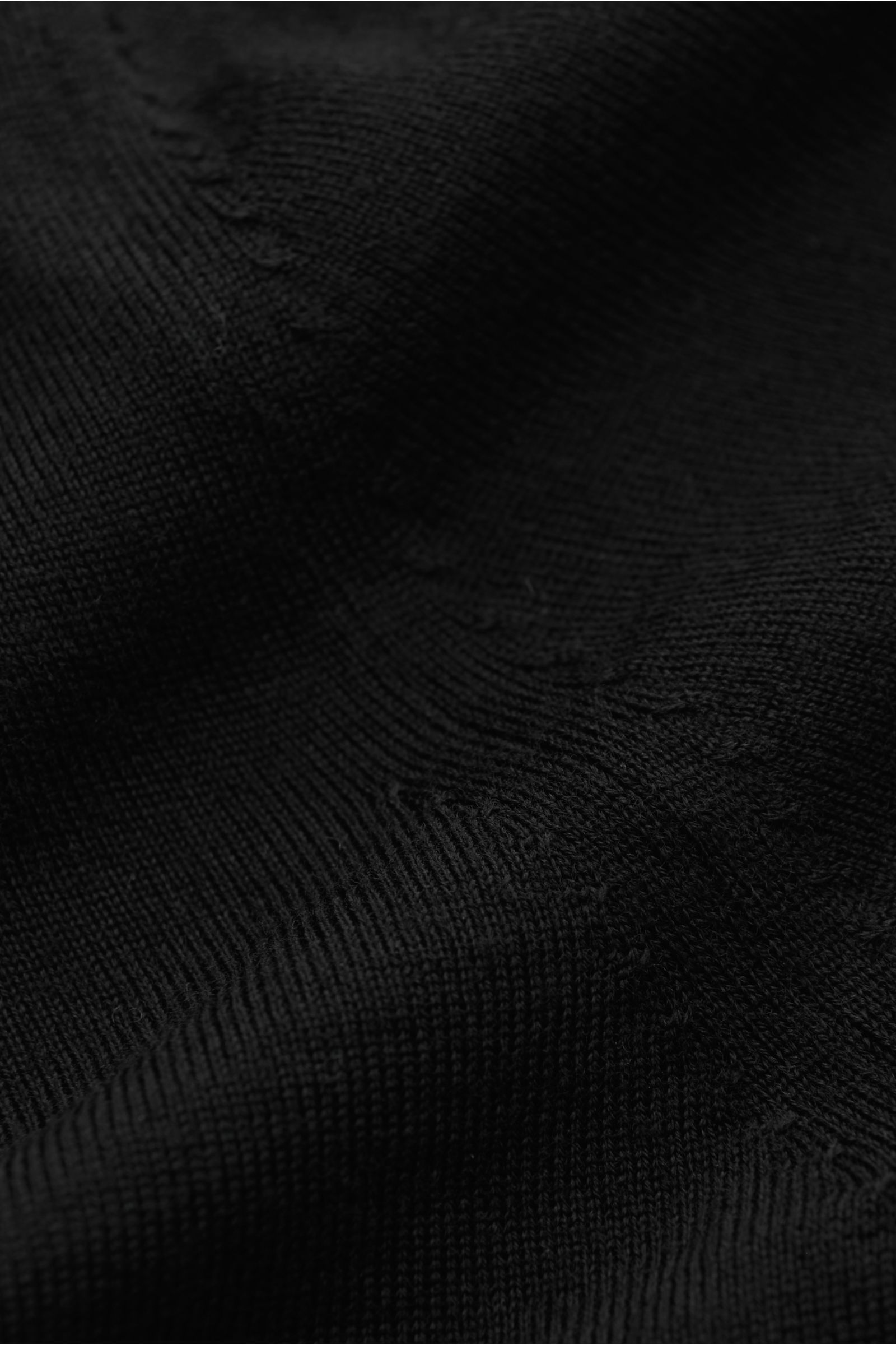 Nahaufnahme des schwarzen von Braun Merino Feinstrickpolo, Perspektive zeigt feines Strickbild, glatte Oberfläche und weiche Merinowolle.