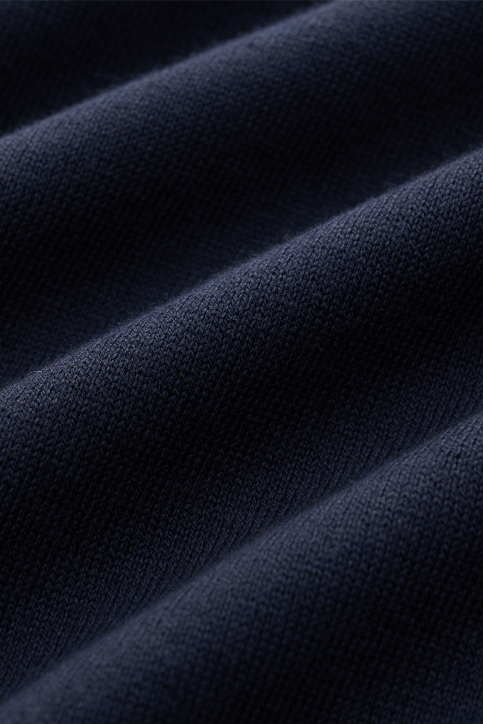 Close-up, angled view of navy fabric showing fine knit texture of 04651/ A trip in a bag Short sleeve jumper 'Pima Cotton' navy. Made of pure Pima cotton, the short sleeve jumper 'Pima Cotton' by 04651 / A TRIP IN A BAG has an airy knit that makes it a go