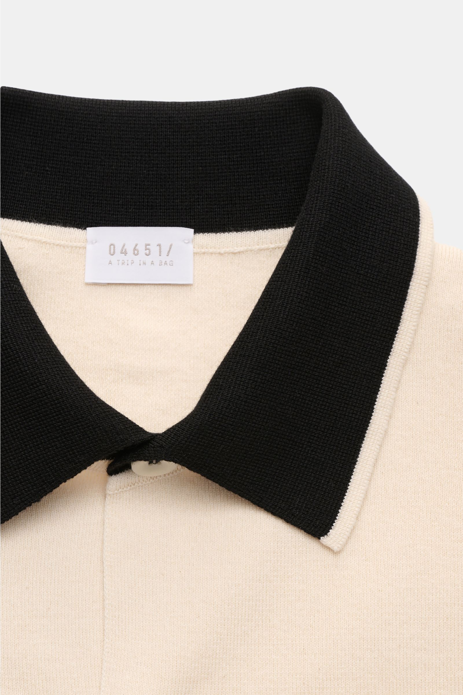 Close-up front view of 04651/ A trip in a bag Short sleeve knit shirt 'Colour Block' cream/black with black collar and cream body.

An eye-catching piece for summer: This short sleeve knit shirt by 04651/ A TRIP IN A BAG has a distinctive colour block 