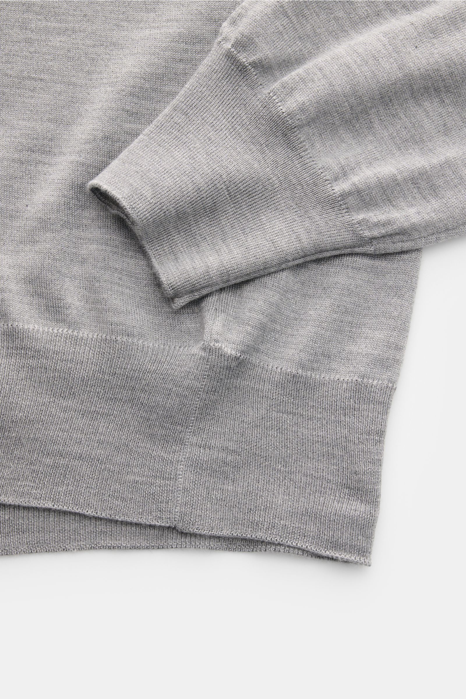 Close-up image of the cuff and hem of the Gran Sasso Fine knit polo light grey mottled, showing the very fine knit and ribbed bands. Luxury you can feel on your skin: This long sleeve knit polo by BRAUN HAMBURG has an exceptionally soft feel and timeless 