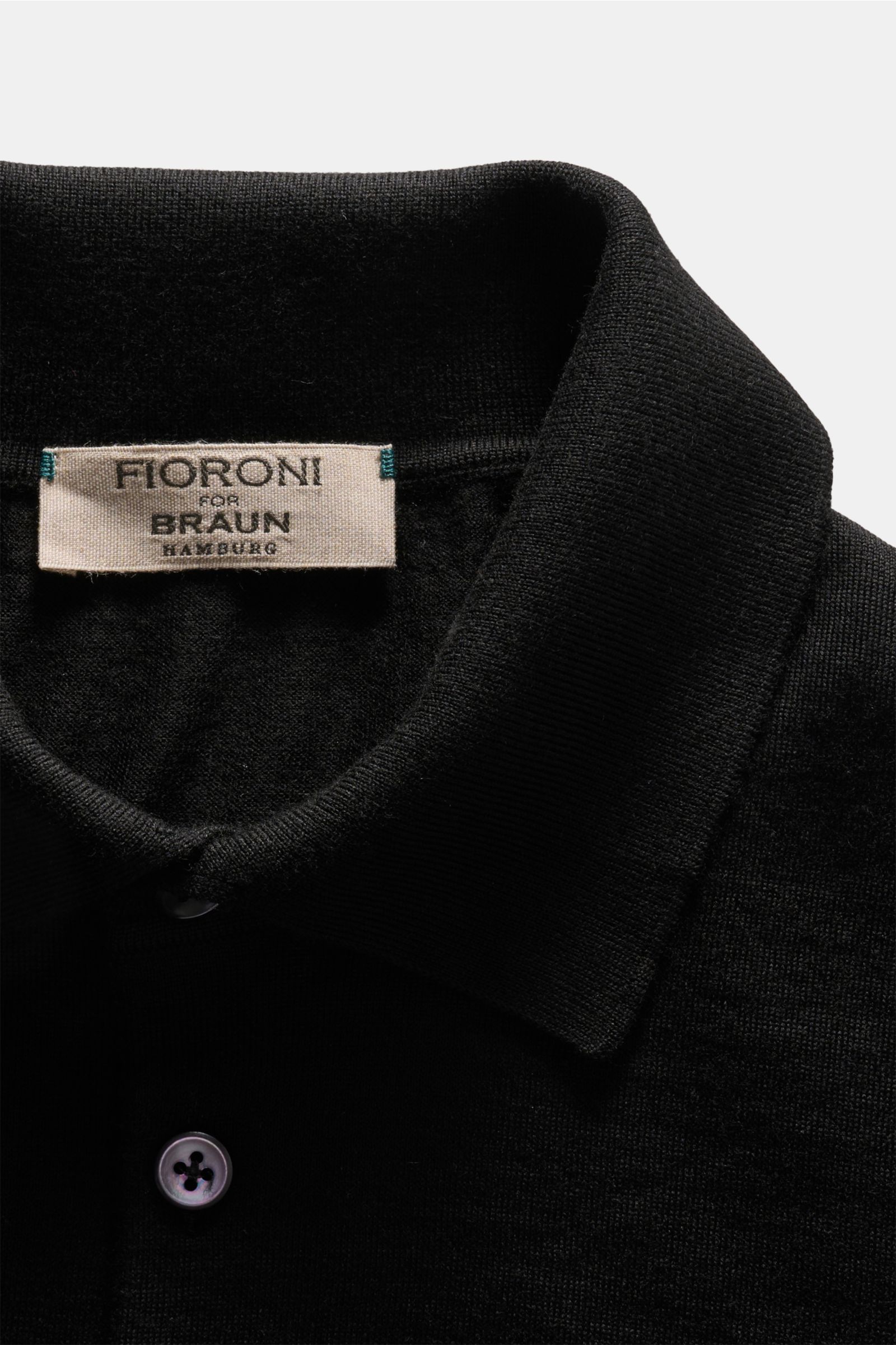 Nahaufnahme des schwarzen Fioroni Strickpolo mit feinem Strickbild, Polokragen und Drei-Knopf-Leiste aus reiner Wolle.