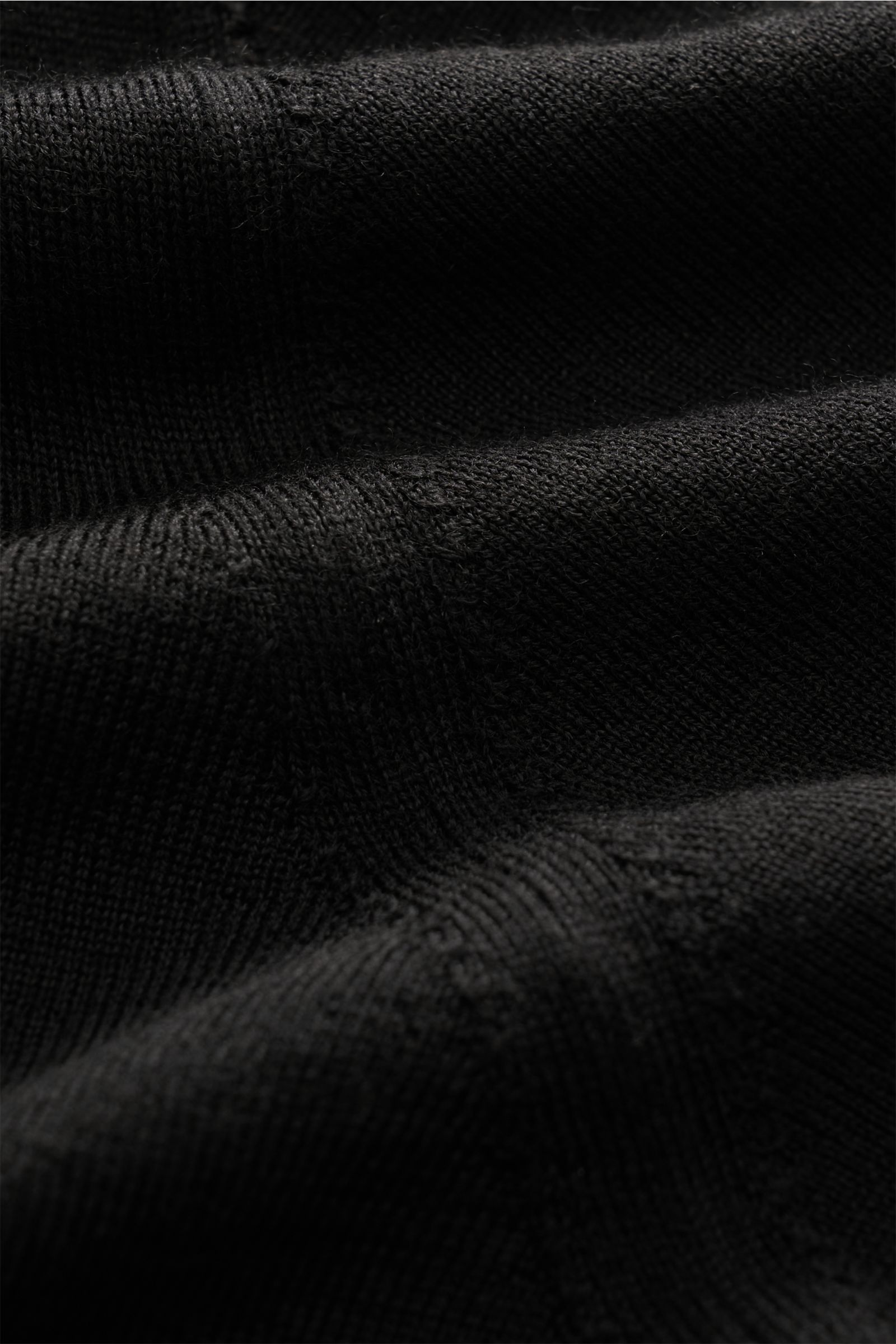 Nahaufnahme des feinen Strickbilds des Fioroni Strickpolo schwarz aus reiner Wolle mit weichem Griff, Regular Fit und Polokragen.