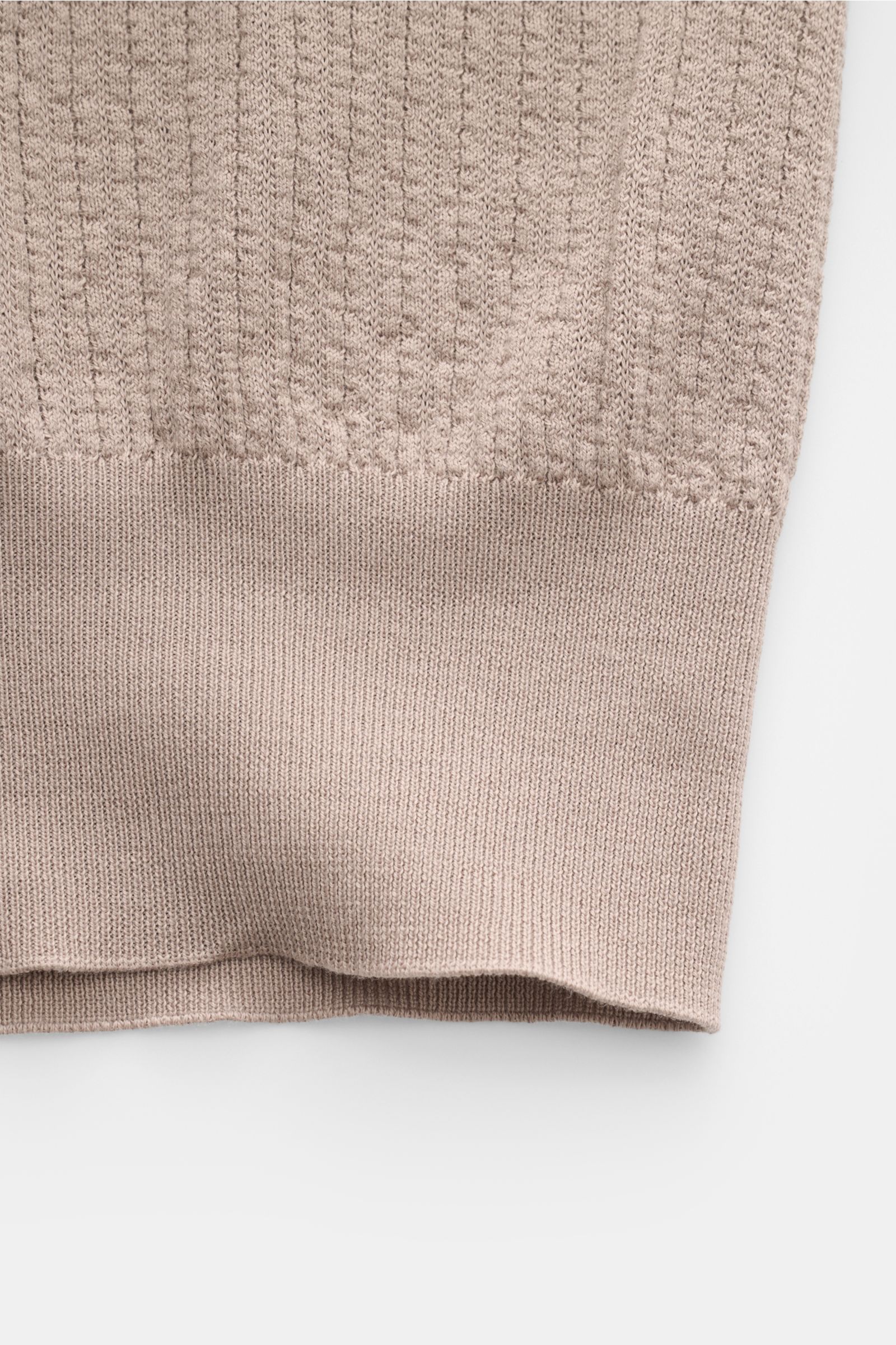 Close-up of the lower section of the Brunello Cucinelli Kurzarm-Strickpolo taupe showing fine, lightweight cotton knit with a soft, smooth texture and ribbed hem, photographed from a top-down perspective. For confident everyday elegance: The timeless shor
