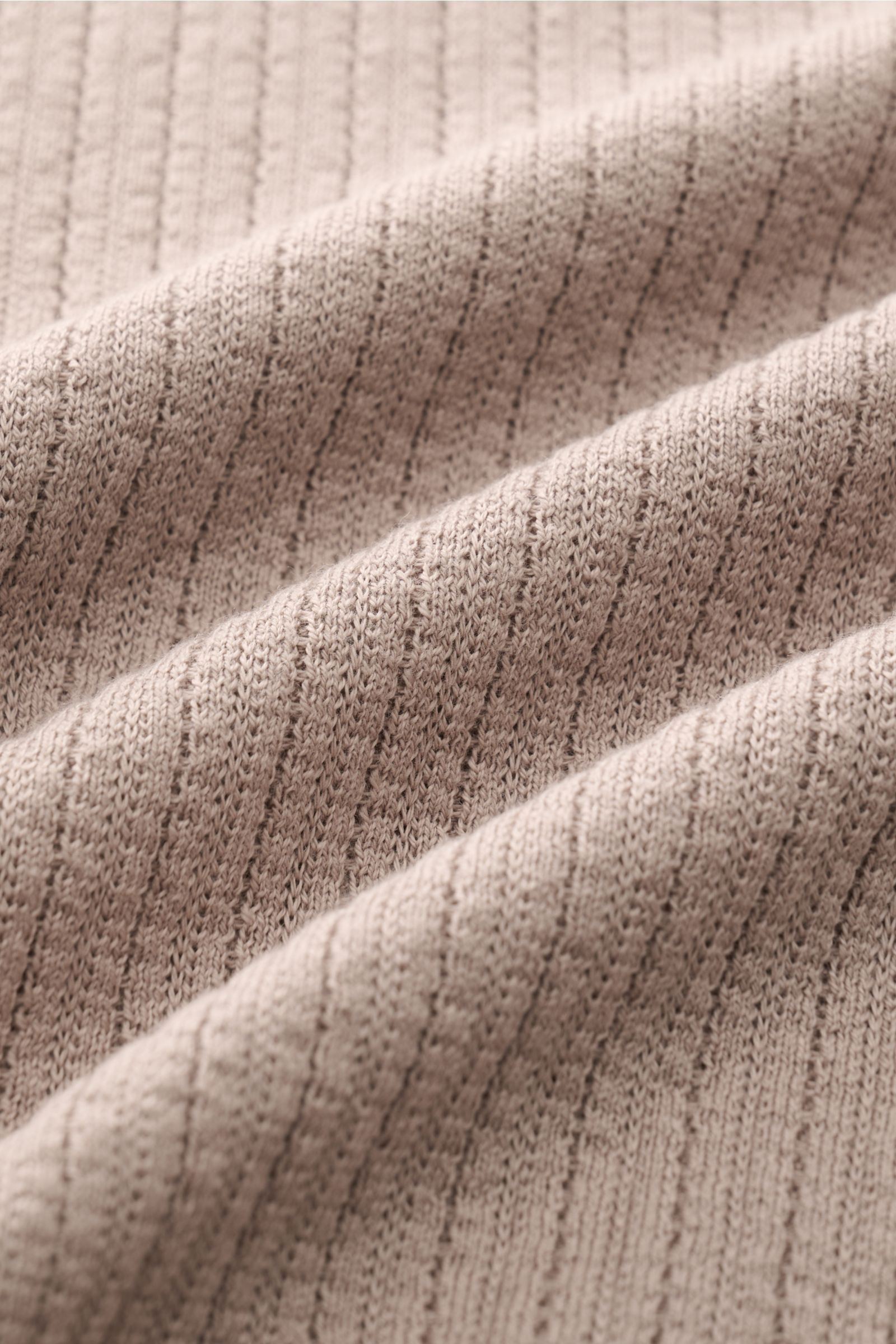 Close-up front view of the finely knitted fabric texture of the Brunello Cucinelli Kurzarm-Strickpolo taupe, showing soft, lightweight cotton knit with a delicate rib pattern and smooth hand feel. Für souveräne Alltags-Eleganz: Das zeitlose Kurzarm-Str