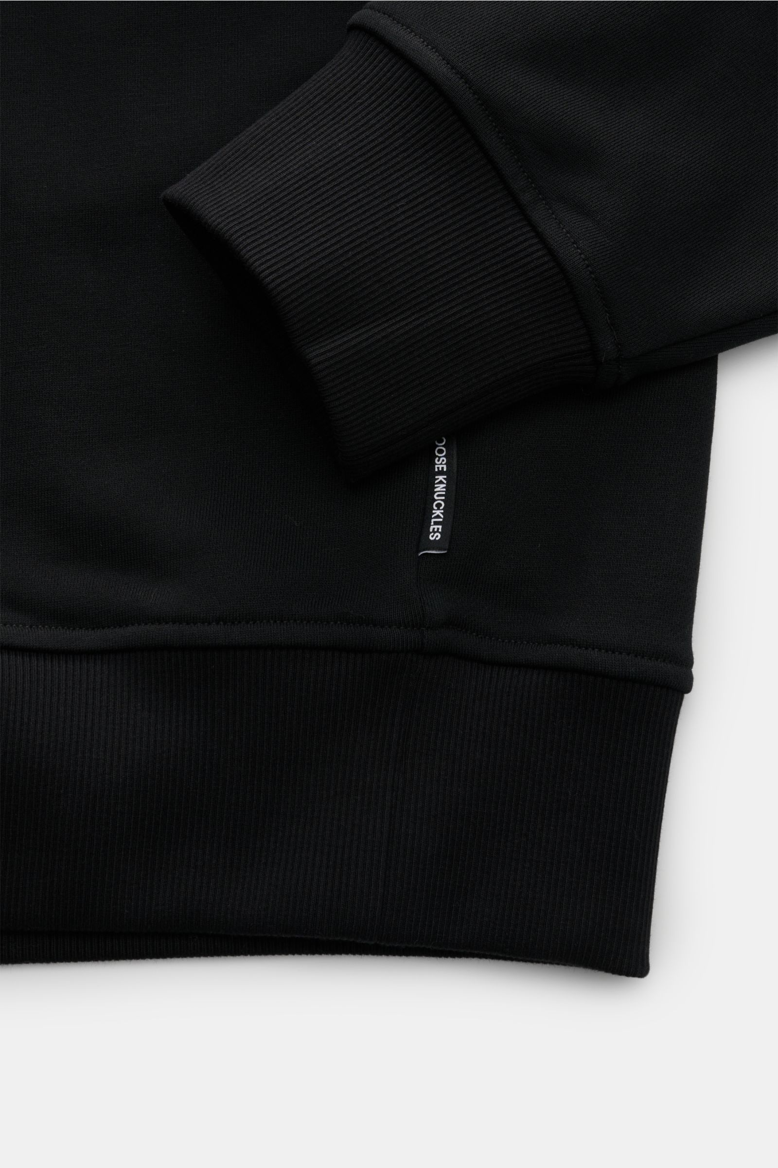 Nahaufnahme des Ärmelbündchens und Saums vom Moose Knuckles Sweat-Troyer 'Hartsfield' schwarz, Regular Fit, weicher Griff, reine Baumwolle, elastische Rippbündchen, Metall-Logo am Oberarm, hoch schließender Kragen mit Zipper.