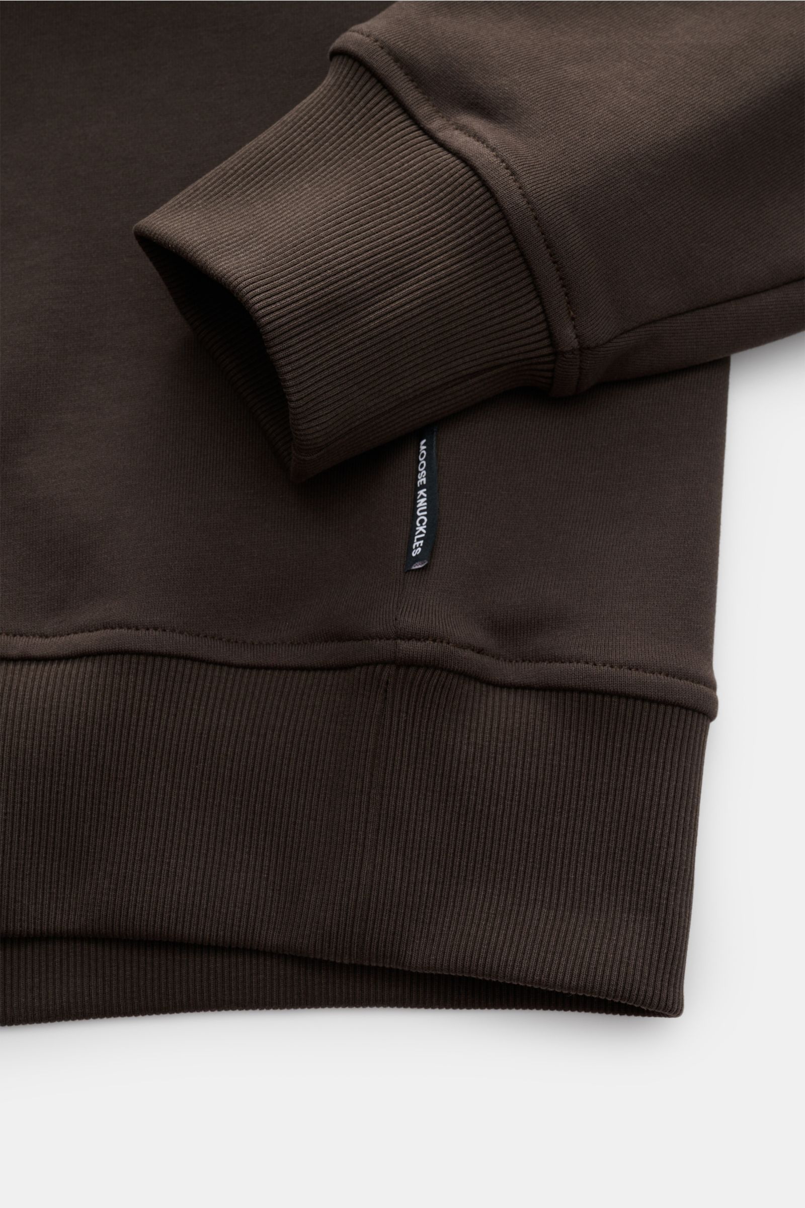 Close-up image from above showing the sleeve cuff and hem of the Moose Knuckles Sweat half-zip jumper 'Hartsfield' grey-brown, sweat made of pure cotton, soft feel, regular fit, high-closing collar with zip, signature metal logo on the upper sleeve, elast
