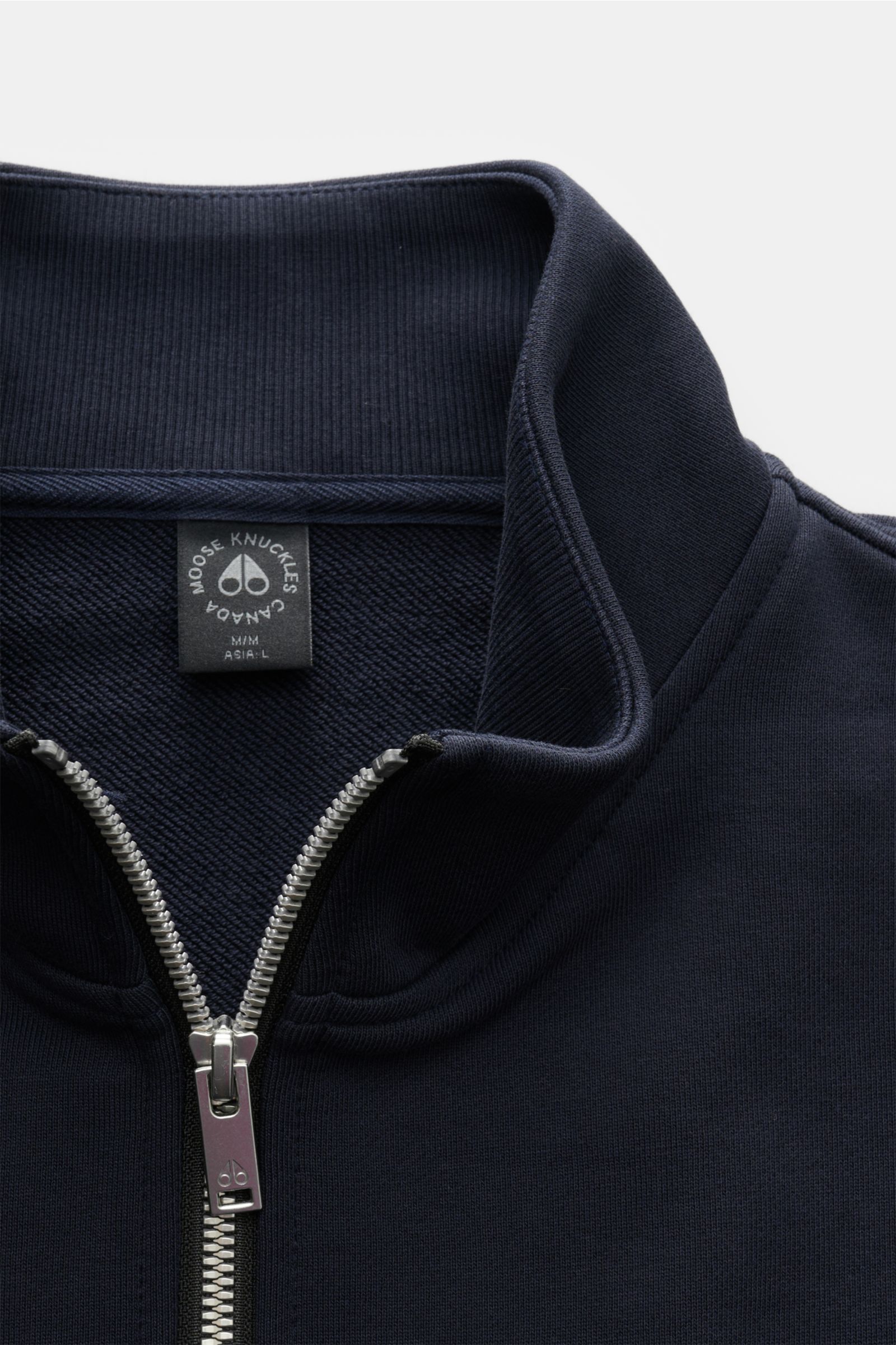 Close-up front view of the navy Moose Knuckles Sweat-Troyer 'Hartsfield' showing the high collar with silver zipper and brand label inside. Leger durch den Herbst: Der Sweat-Troyer von MOOSE KNUCKLES überzeugt als vielseitiges Basic für sportive und ze