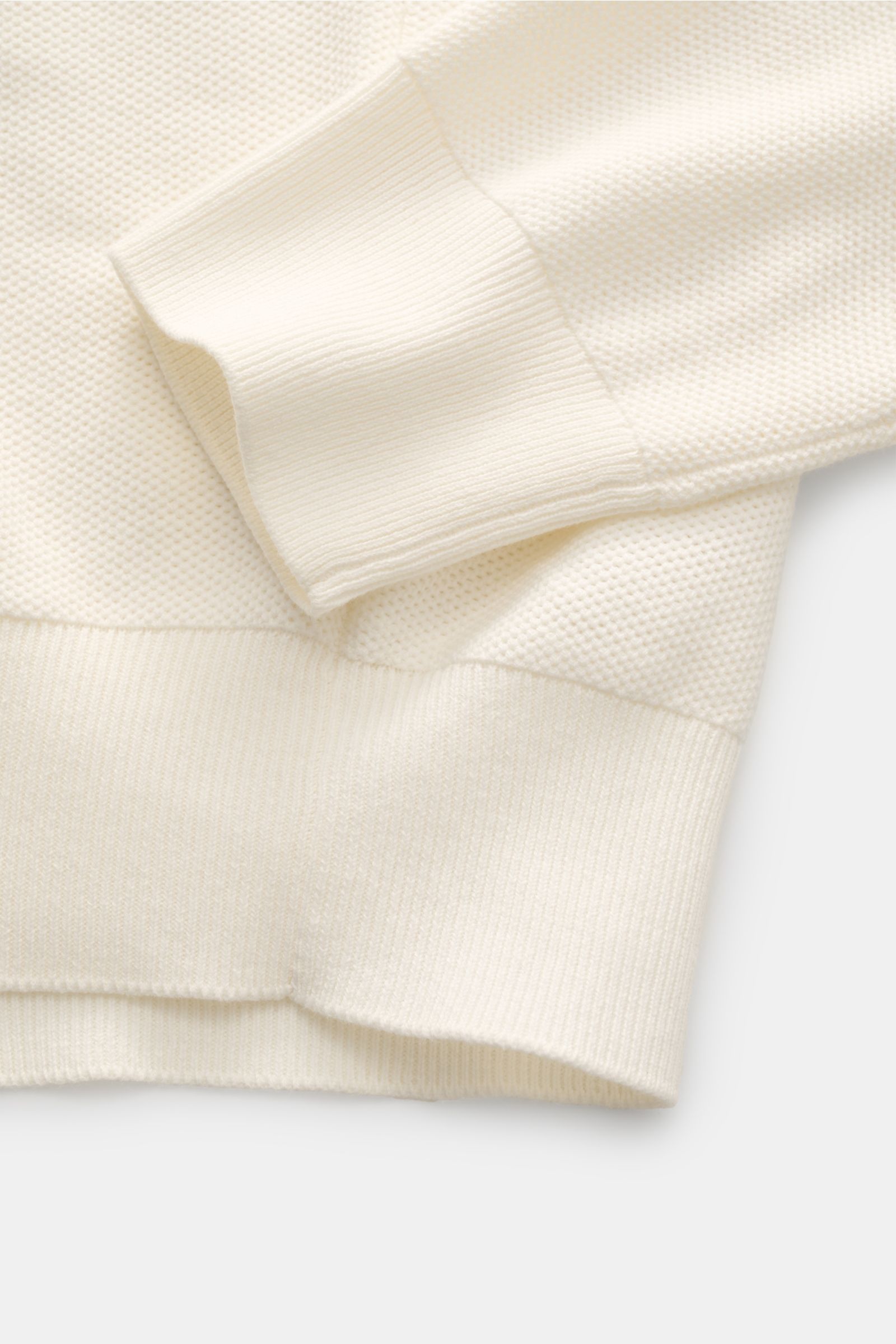 Nahaufnahme des Polo Ralph Lauren Troyer offwhite von schräg oben, zeigt dreidimensionalen Strukturstrick, weiche Baumwollqualität, Rippbündchen und feines Strickbild.