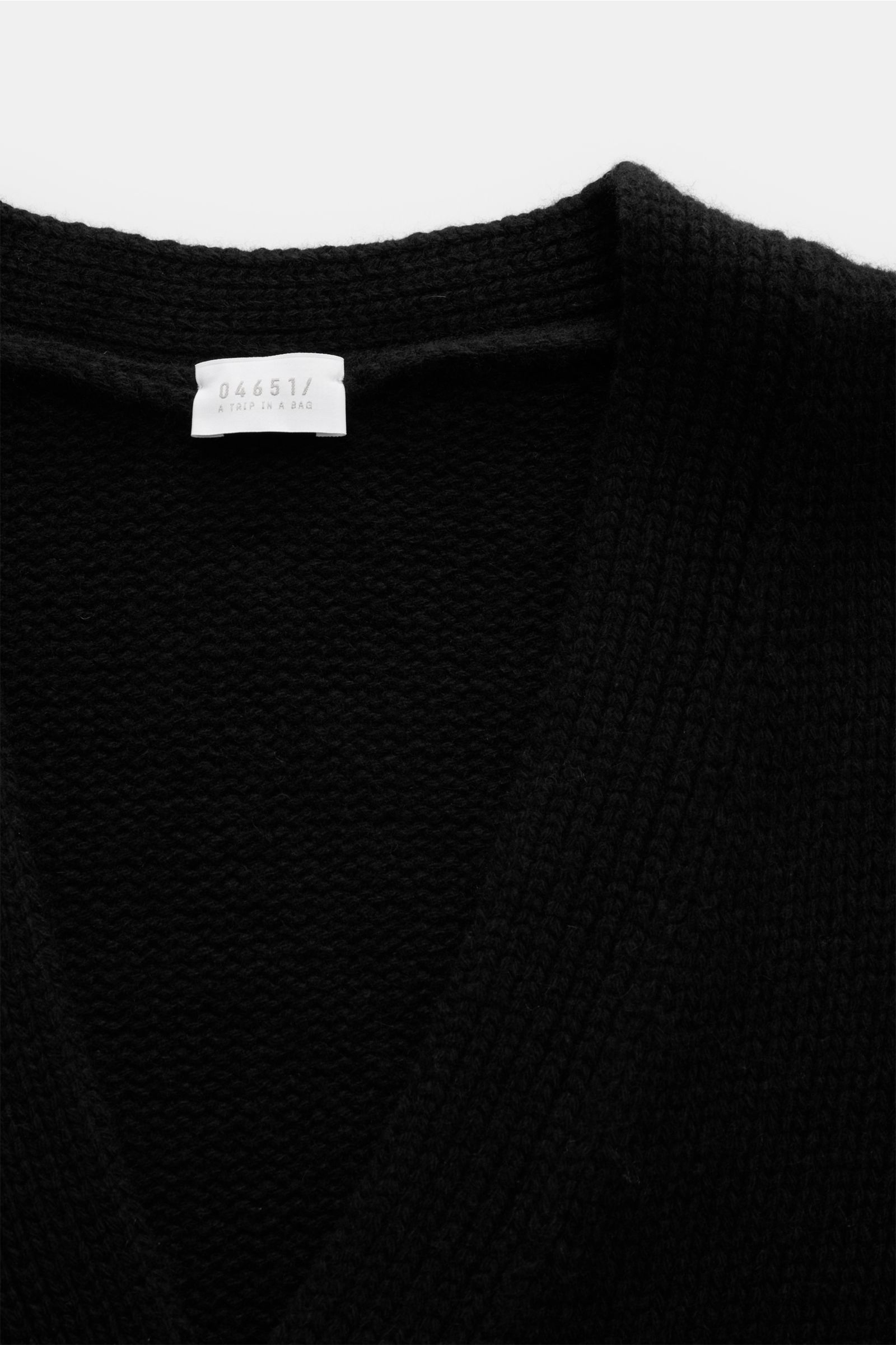 Schwarzer 04651/ A trip in a bag Cashmere Cardigan, Slim Fit, V-Ausschnitt, Vier-Knopf-Leiste, aufgesetzte Hüfttaschen, reiner Cashmere, grobes Strickbild, sehr weicher Griff, komfortable Rippbündchen, Nahaufnahme von oben.