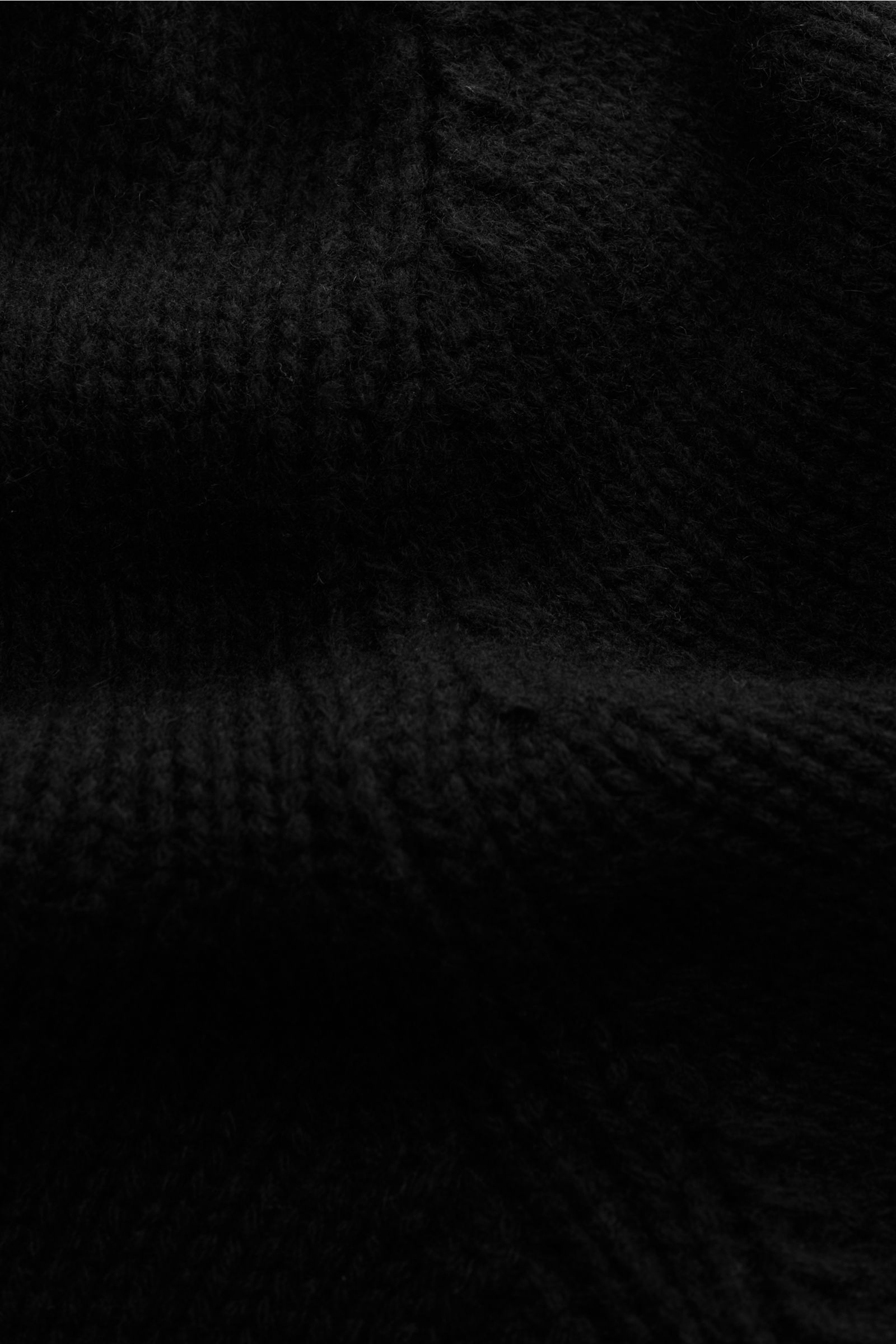 04651/ A trip in a bag Cashmere Cardigan schwarz, Nahaufnahme aus schräger Perspektive mit grobem Strickbild, reiner Cashmere, sehr weich, Slim Fit, V-Ausschnitt, Vier-Knopf-Leiste, aufgesetzte Hüfttaschen, Rippbündchen.