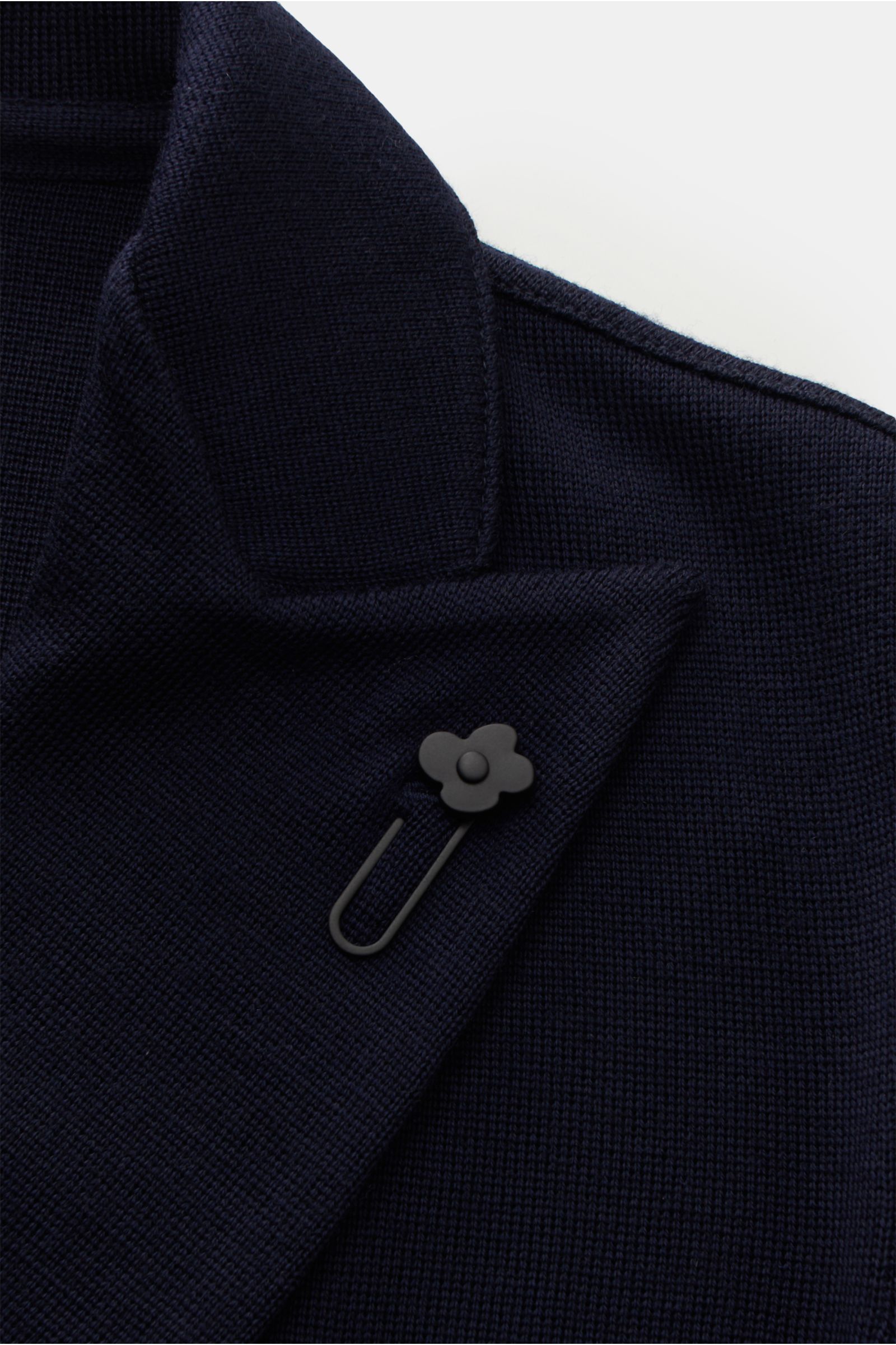 Nahaufnahme aus schräger Perspektive des navyfarbenen Lardini Strickblazers mit weichem Griff, feinem Strickbild, Revers und Blütenpin.