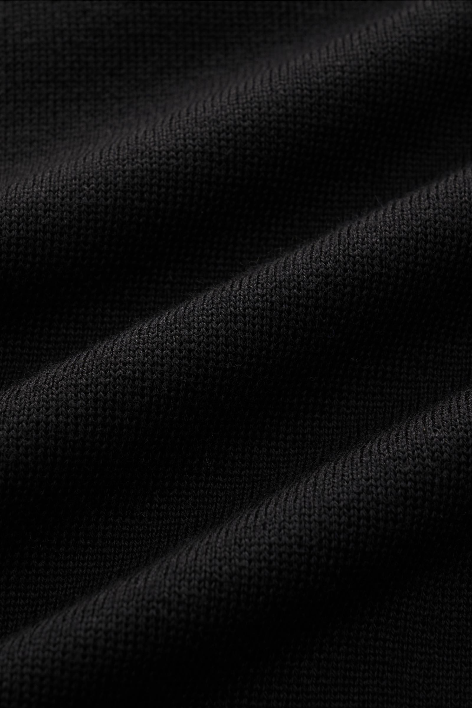 Close-up image of the fine knit texture of the Lardini Strickblazer schwarz fabric, photographed from a top-down perspective. Mit klassischer Silhouette und gefertigt aus reiner Wolle perfektioniert der stilvolle Strickblazer von LARDINI Ihre Smart Cas