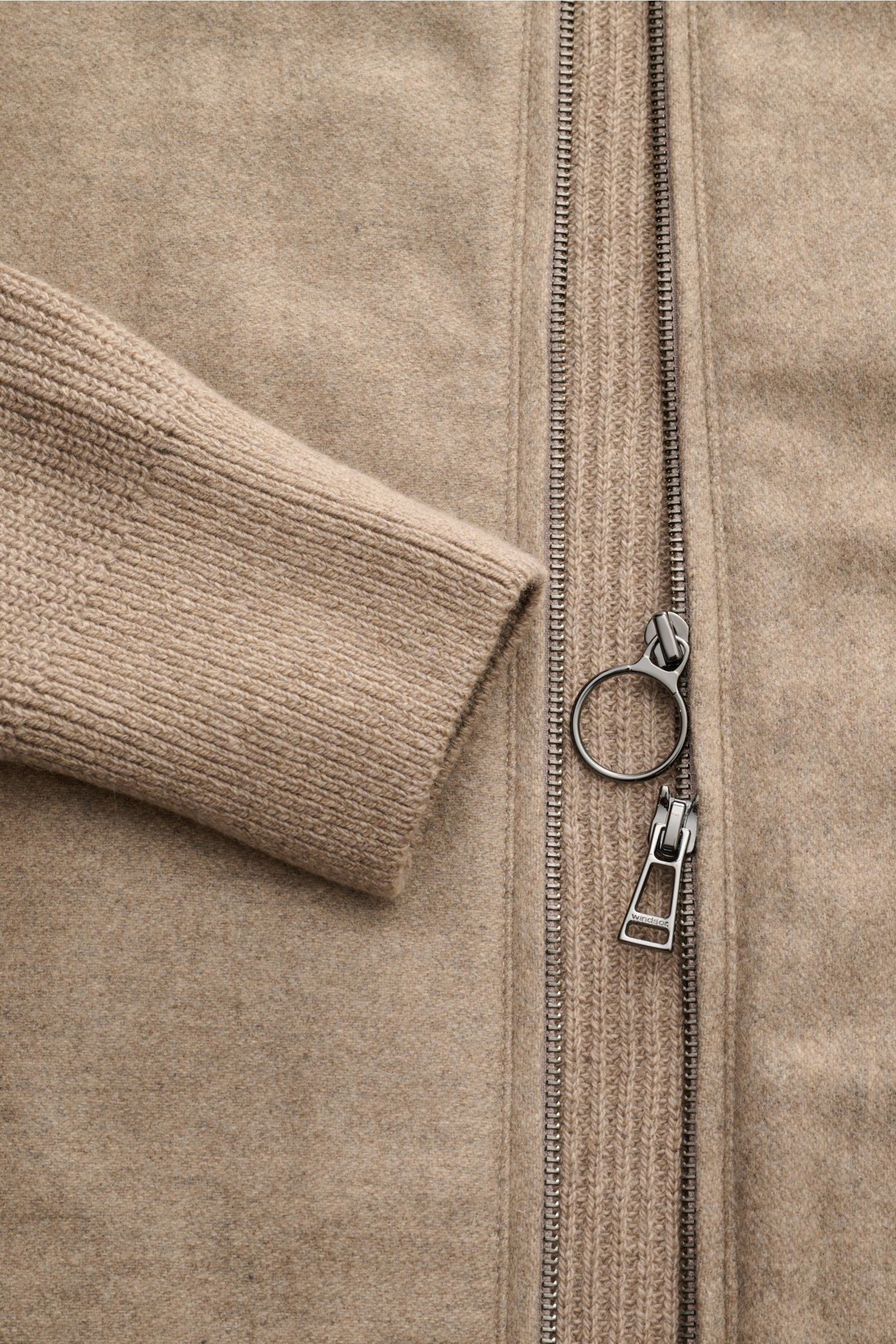 Nahaufnahme des beigefarbenen Windsor Cashmere Strick-Blouson 'Ecosio' mit Rippstrick-Ärmelbündchen und robustem Zwei-Wege-Reißverschluss.