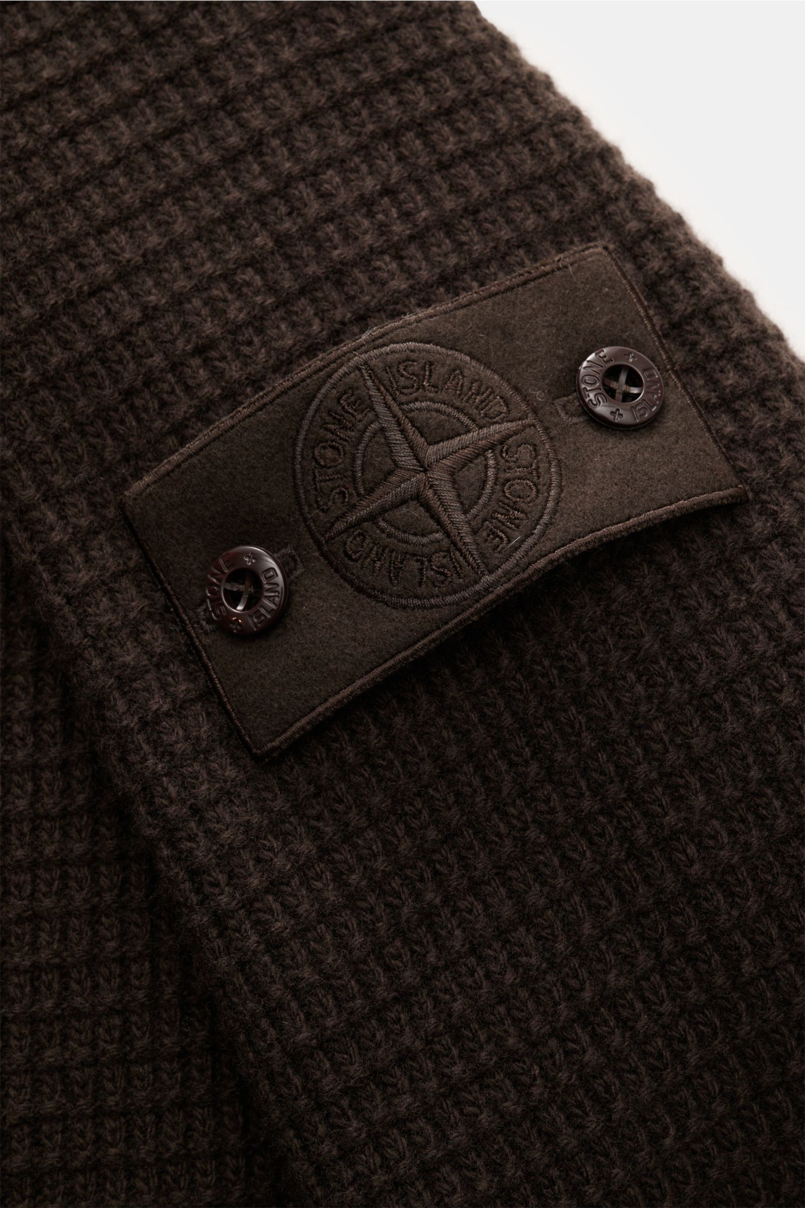 Nahaufnahme der tonalen Kompass-Badge auf der Stone Island Strickjacke 'Ghost Piece' dunkelbraun mit markantem Strukturstrick.