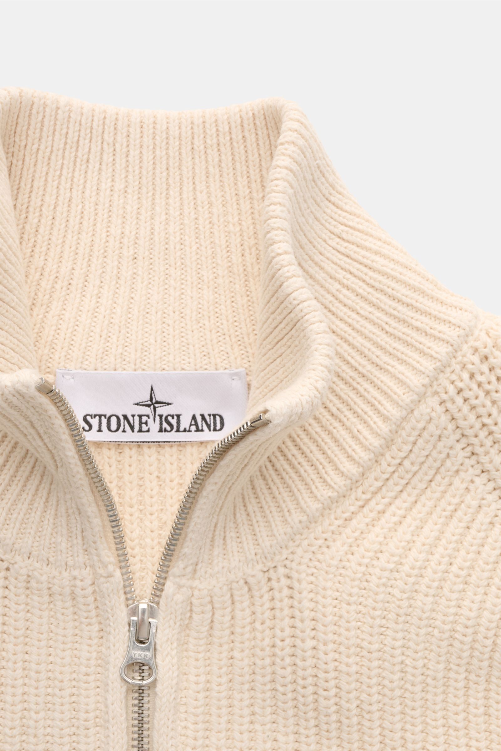 Close-up front view of the Stone Island Strickjacke 'Raw Beauty' creme, showing the high stand collar, two-way zipper, and detailed ribbed cotton knit. Ein Essential für moderne Casual-Looks: Diese Strickjacke von STONE ISLAND überzeugt mit markantem P