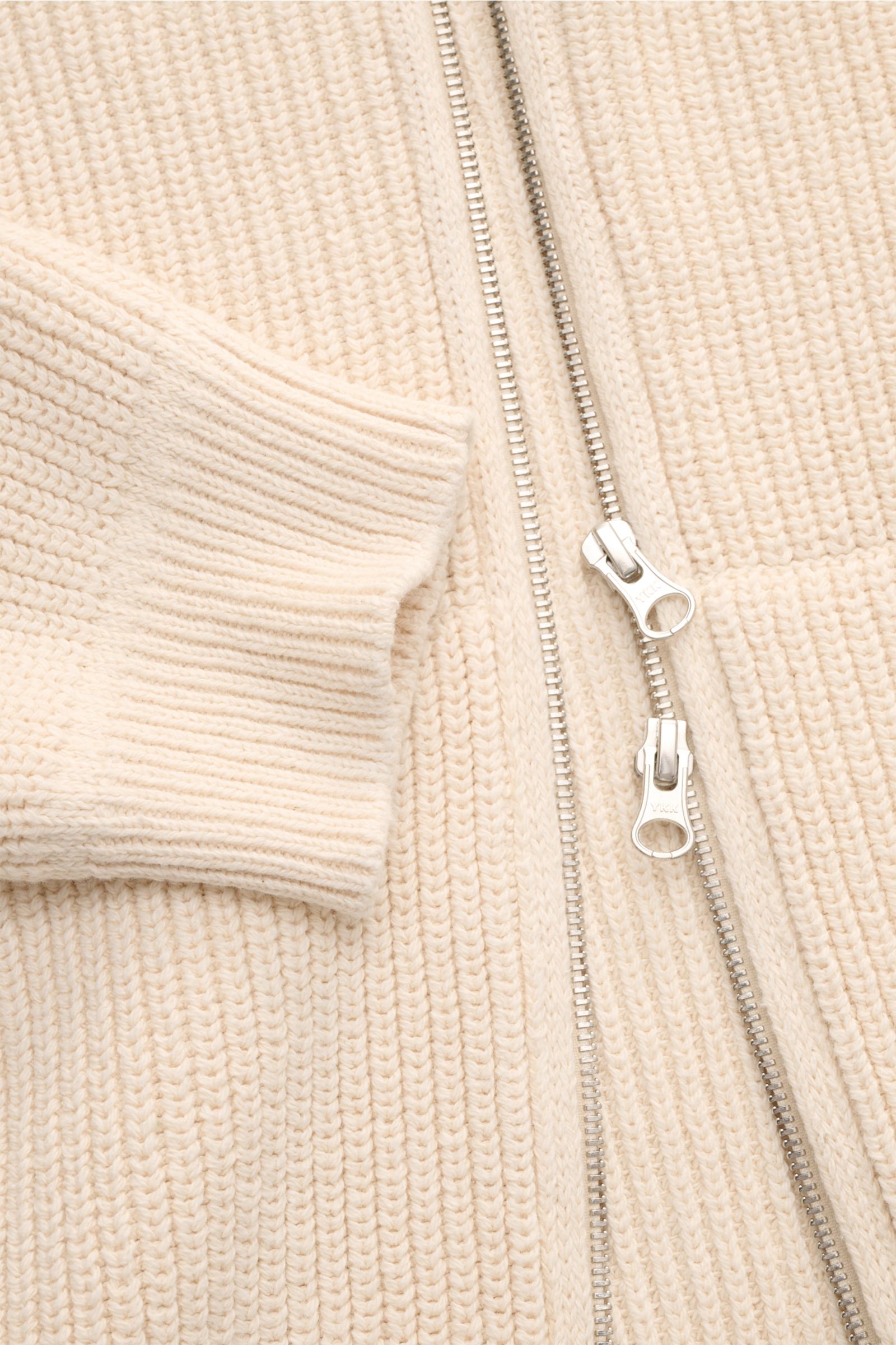 Close-up front view of Stone Island Strickjacke 'Raw Beauty' creme cardigan showing cream patent knit, ribbed cuff, and silver two-way zipper.

Ein Essential für moderne Casual-Looks: Diese Strickjacke von STONE ISLAND überzeugt mit markantem Patentstr