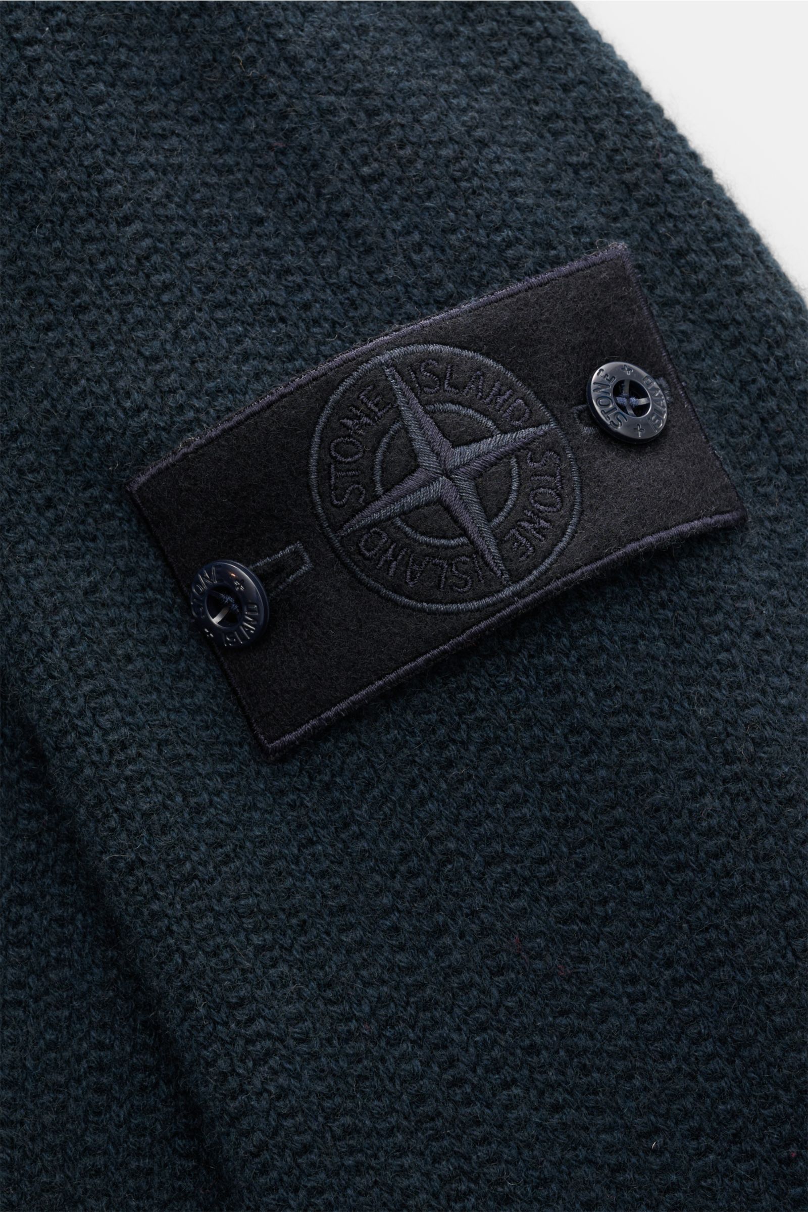 Nahaufnahme aus schräger Perspektive der tonalen Kompass-Badge auf der Stone Island Cashmere Strickjacke 'Ghost Piece' navy mit mittelfeinem Strickbild.