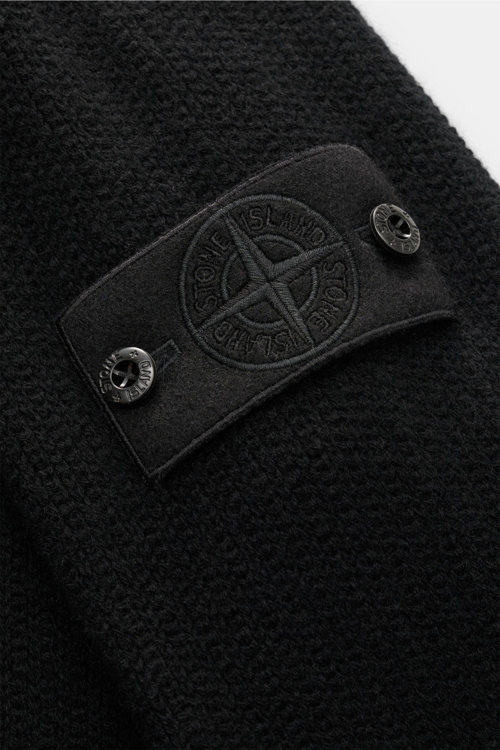 Nahaufnahme der tonalen Kompass-Logoplatte auf dem schwarzen Stone Island Cashmere Strickjacke 'Ghost Piece' aus mittelfeinem, weichem Cashmere mit markanten Nähten.