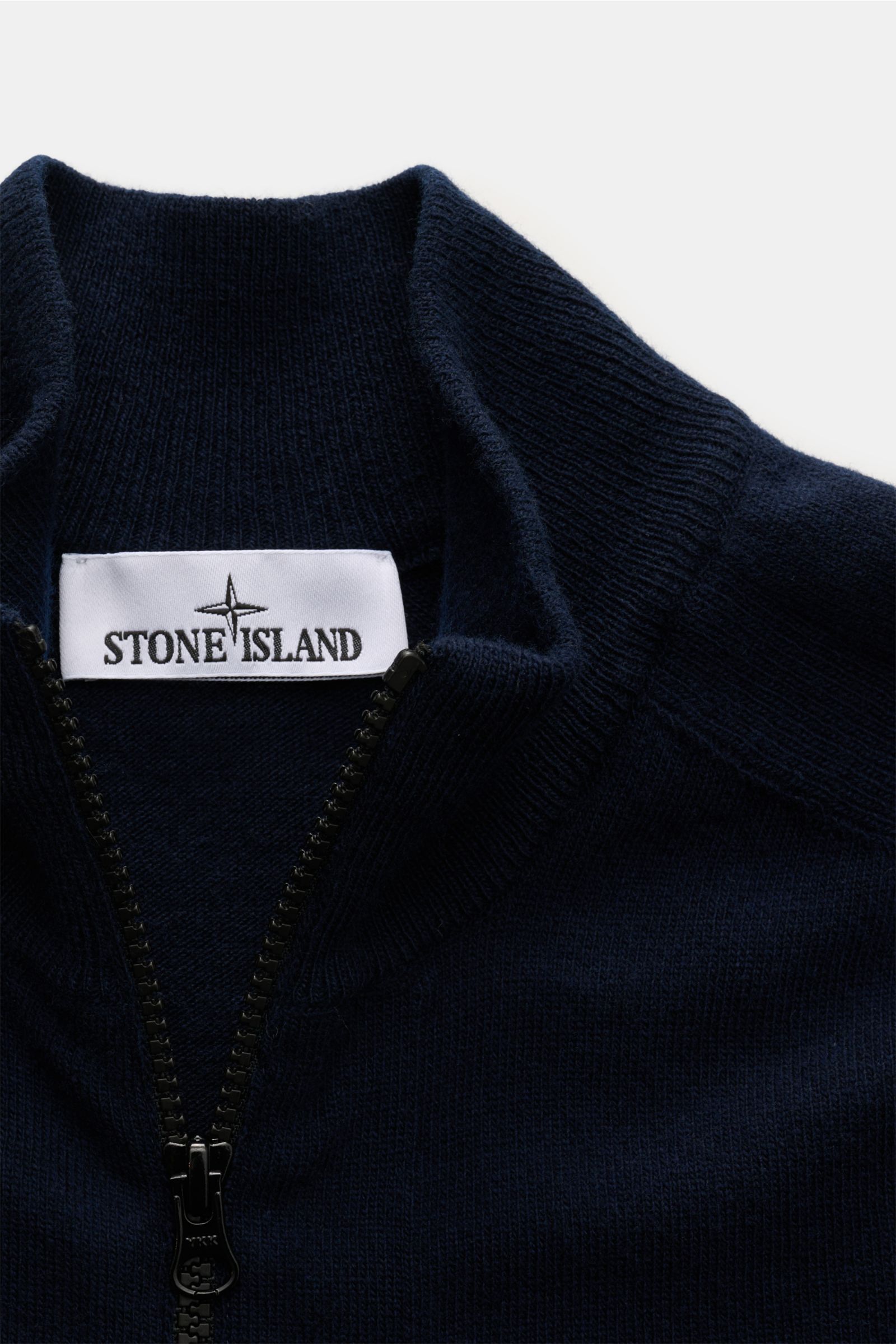 Stone Island Strickjacke navy aus weicher, zertifizierter Geelong-Schurwolle, Slim Fit mit Zwei-Wege-Reißverschluss, Stehkragen, Raglanärmeln, Kompass-Badge, Rippbündchen, Detailaufnahme von oben.