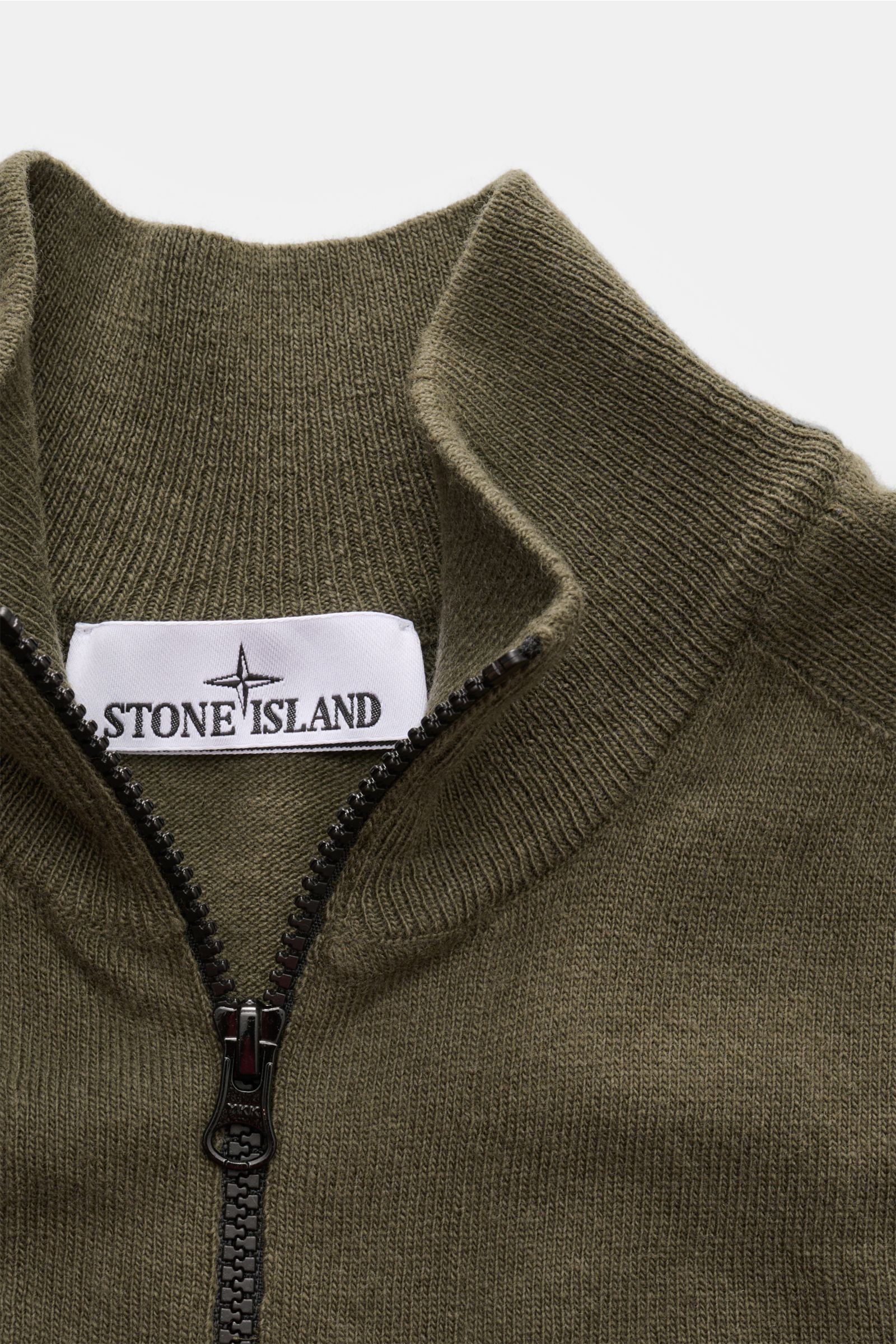 Stone Island Strickjacke oliv aus zertifizierter Geelong-Schurwolle, Slim Fit mit Zwei-Wege-Reißverschluss, Stehkragen, Raglanärmel, Kompass-Badge, Rippbündchen, Detailaufnahme von oben.