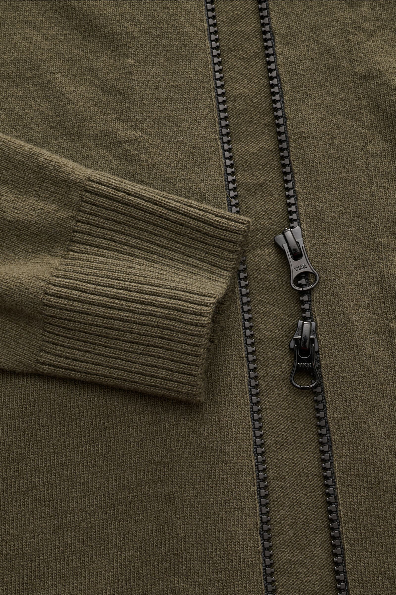 Nahaufnahme der Stone Island Strickjacke oliv aus zertifizierter Geelong-Schurwolle mit zwei-Wege-Reißverschluss und Rippbündchen.