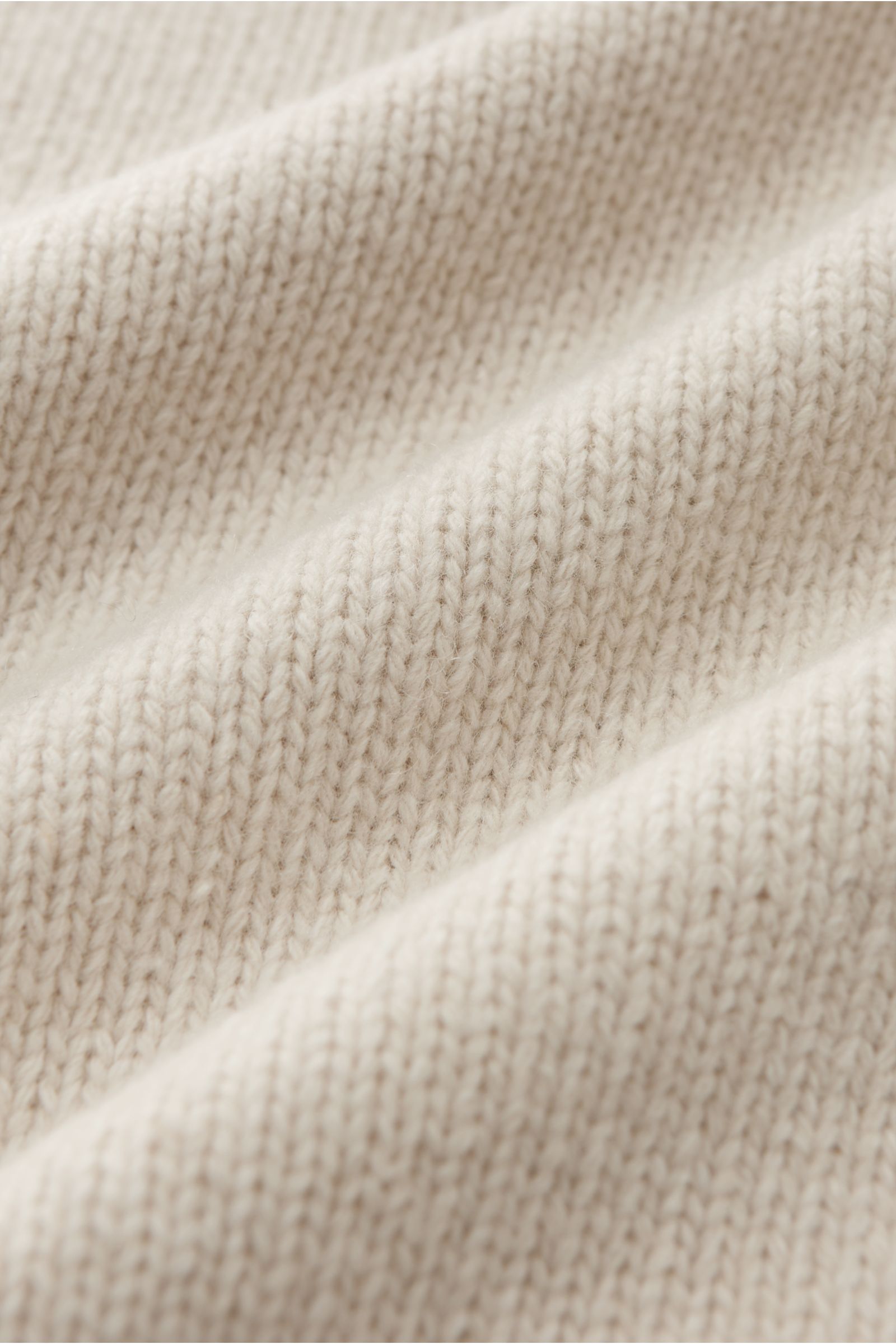 Stone Island Strickjacke 'Lambswool' sand aus weichem Wollmix, mittelfeinem Strickbild, Filz-Details, Kompass-Badge, nah fotografiert.