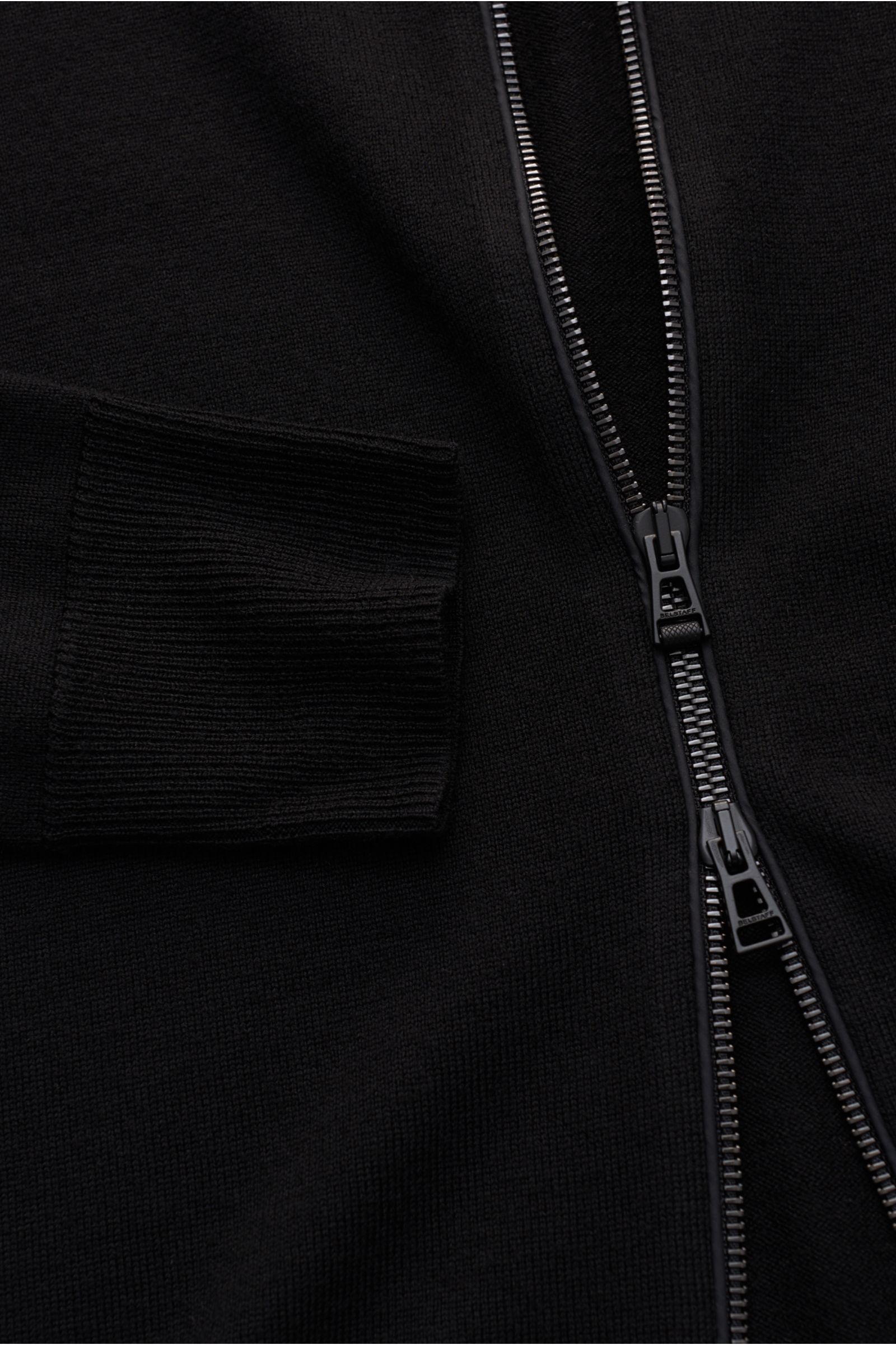 Close-up front view of Belstaff Strickjacke 'Kelby' schwarz showing fine wool knit, two-way zipper, ribbed cuff, and detailed stitching.

Description: Bei BELSTAFF erinnert auch die Strickjacke 'Kelby' an die Wurzeln des Labels: Steppdetails an Schultern 