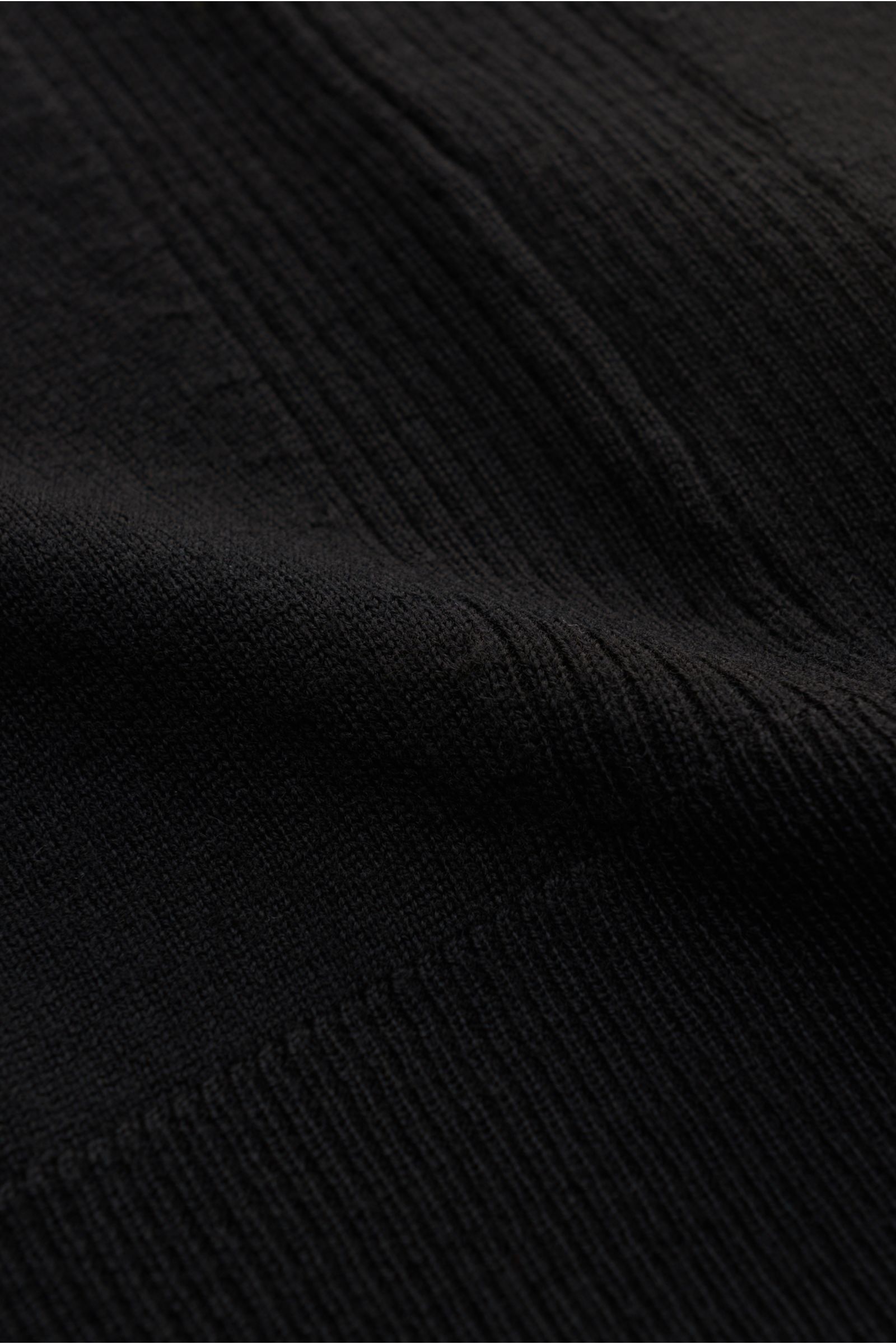 Close-up front view of Belstaff Strickjacke 'Kelby' schwarz showing fine knit texture, quilted shoulder details, and ribbed cuffs.

Description: Bei BELSTAFF erinnert auch die Strickjacke 'Kelby' an die Wurzeln des Labels: Steppdetails an Schultern und