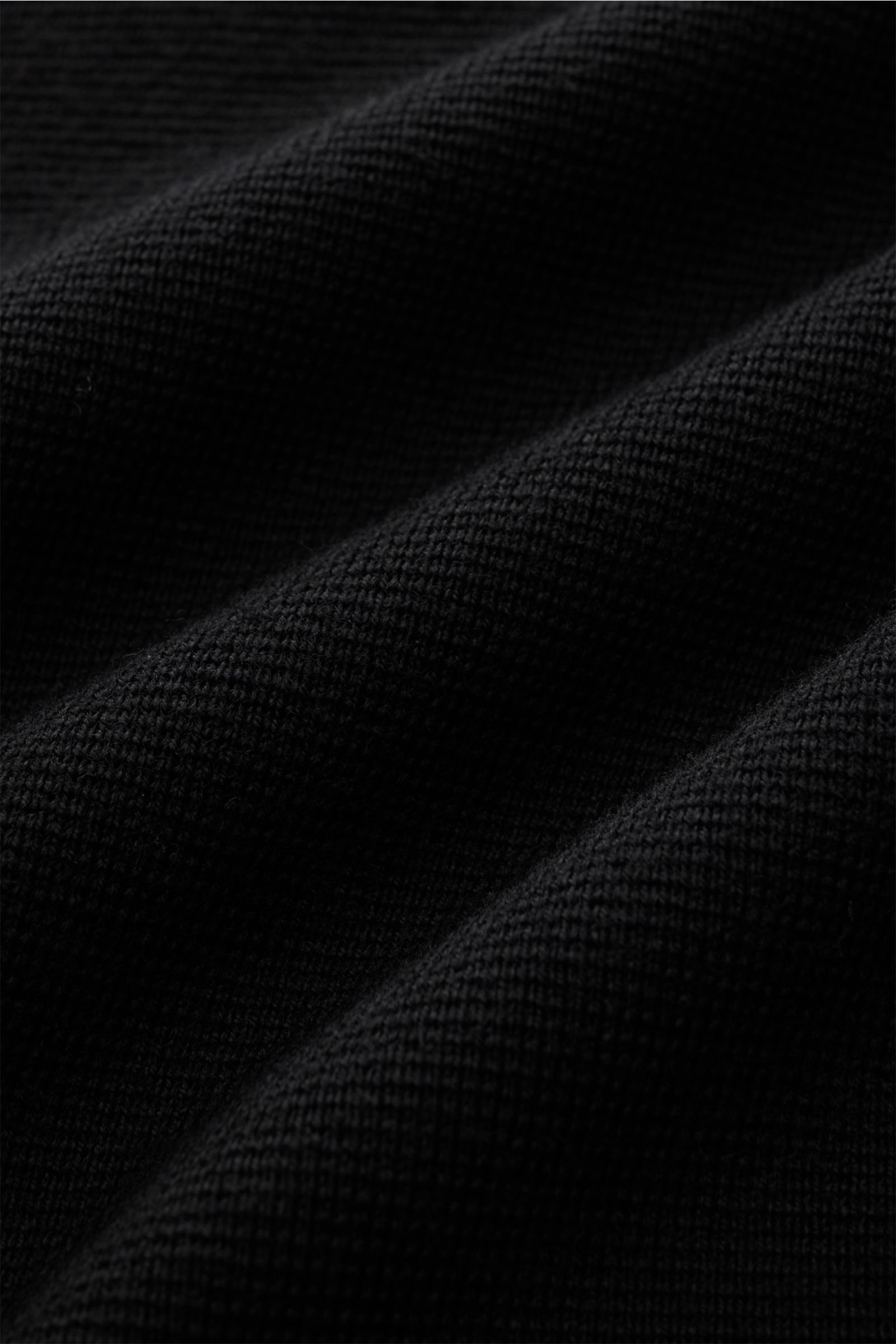 Close-up view of the black fabric texture of the Filippo de Laurentiis Merino Cardigan schwarz, showing fine knit detail. Für zeitlose Looks im Winter: Der Cardigan von FILIPPO DE LAURENTIIS garantiert Komfort sowie stilvolle Eleganz und hält mit seine