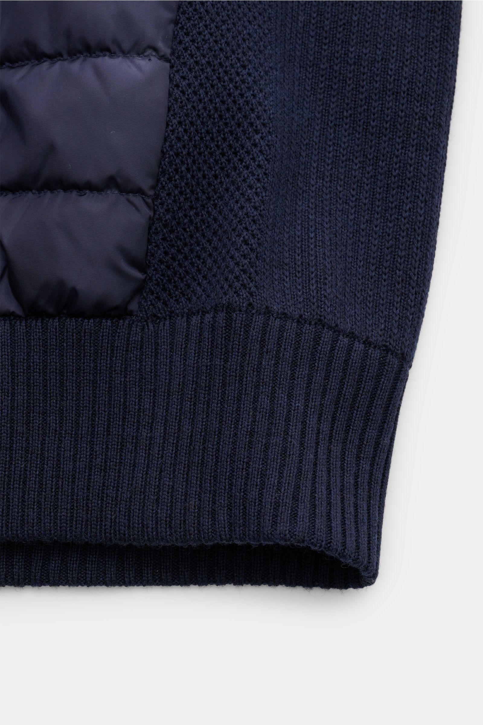 Nahaufnahme der unteren Kante der Canada Goose Strickjacke 'Hybridge Knit' navy, zeigt Wollstrick, Daunen-Front und Rippbündchen.