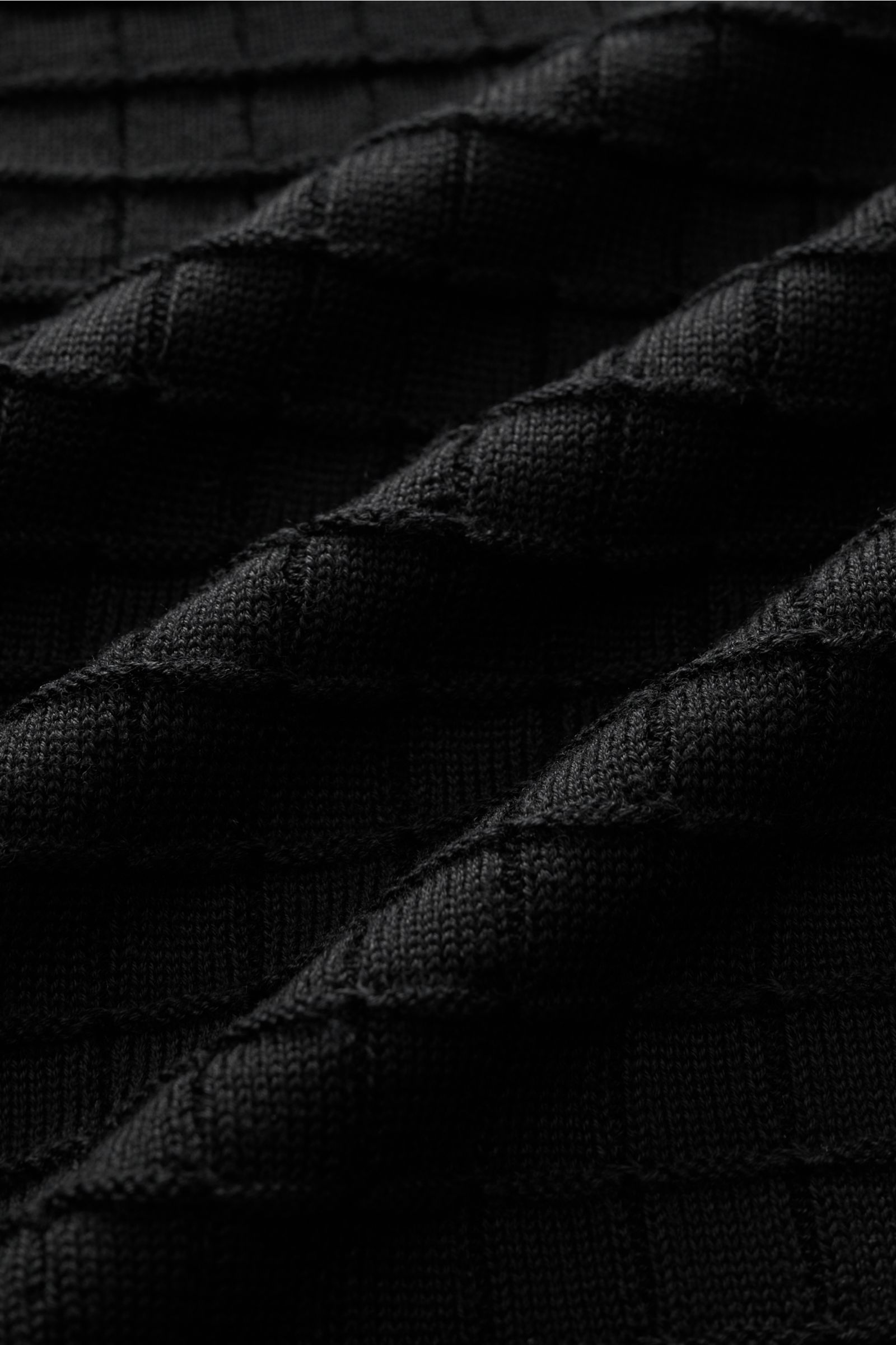 Emporio Armani Strickjacke schwarz in Nahaufnahme, feines, markant strukturiertes Strickmuster, weicher Griff, tonales Logo-Stitching sichtbar.