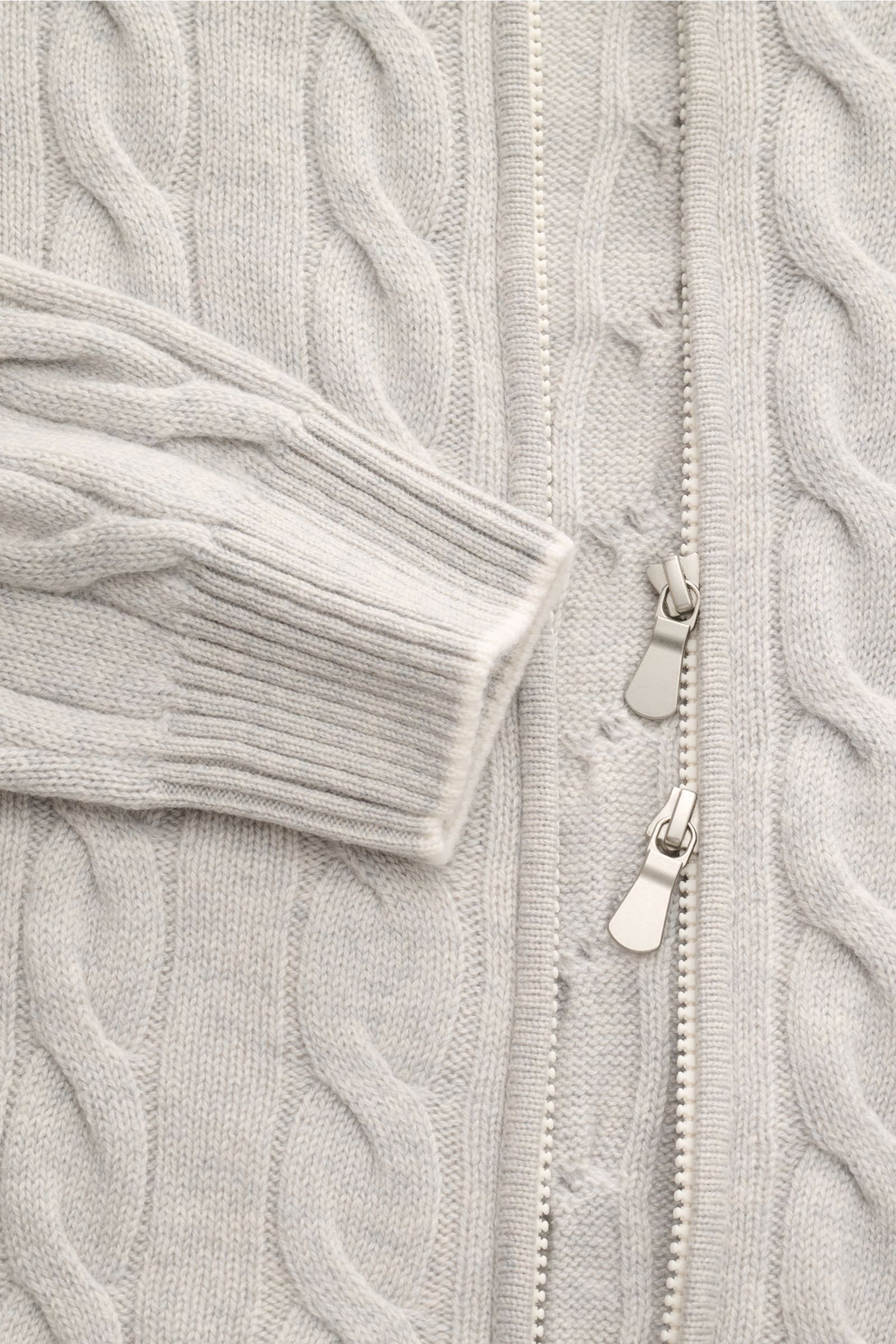Close-up front view of Gran Sasso Cashmere Strickjacke hellgrau meliert with cable knit, two-way zipper, and ribbed cuff.

Description: Luxuriöses Basic für die Übergangszeit: Diese edle Strickjacke von GRAN SASSO aus softem Cashmere im Zopfstrick-Desi
