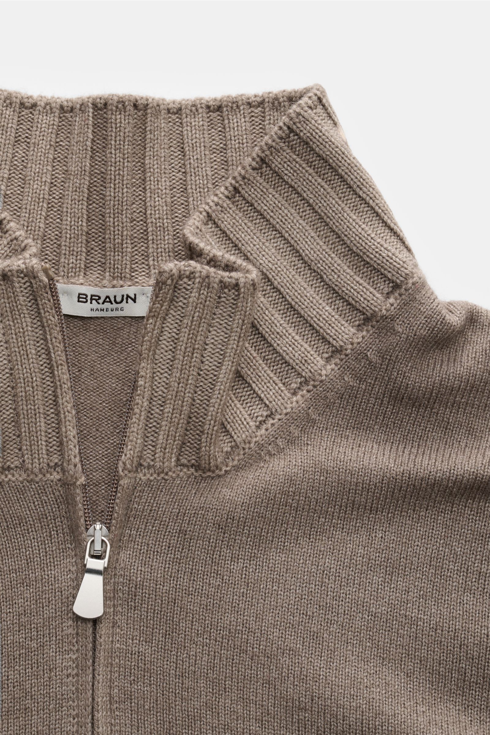 Close-up front view of the BRAUN Hamburg Strickjacke taupe cardigan, showing soft knit fabric, ribbed standing collar, zipper, and fine stitch detail. Zeitlose Eleganz trifft Komfort: Die besonders weiche sowie wärmende Strickjacke von BRAUN HAMBURG wi