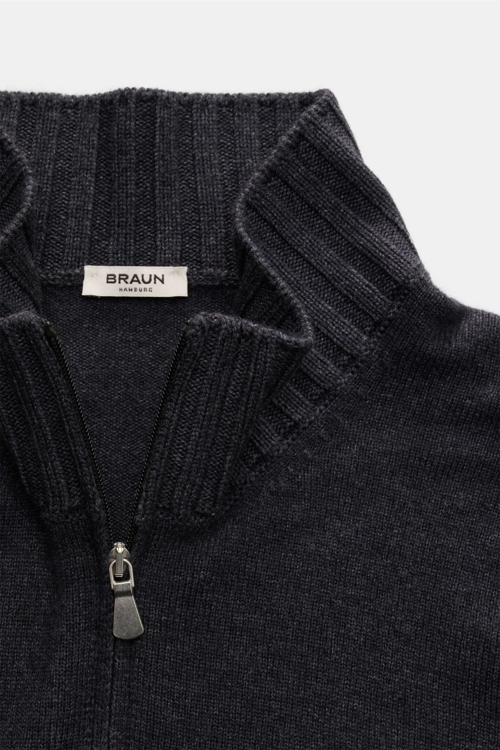 Close-up front view of the BRAUN Hamburg Cardigan anthracite mottled showing the zip and standing collar with flexible ribbed bands.

Description: 
Timeless elegance meets comfort: This soft and warm cardigan by BRAUN HAMBURG is a versatile layering pi