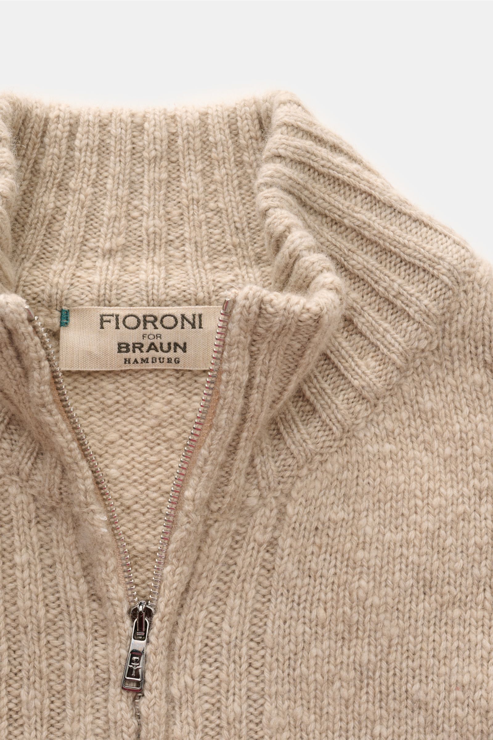 Close-up front view of Fioroni Cashmere Strickjacke sand meliert cardigan showing reiner Cashmere, very soft feel, mittelfeines Strickbild, light bouclé effect, slim fit, two-way zipper, slanted hip pockets, and flexible rib cuffs.