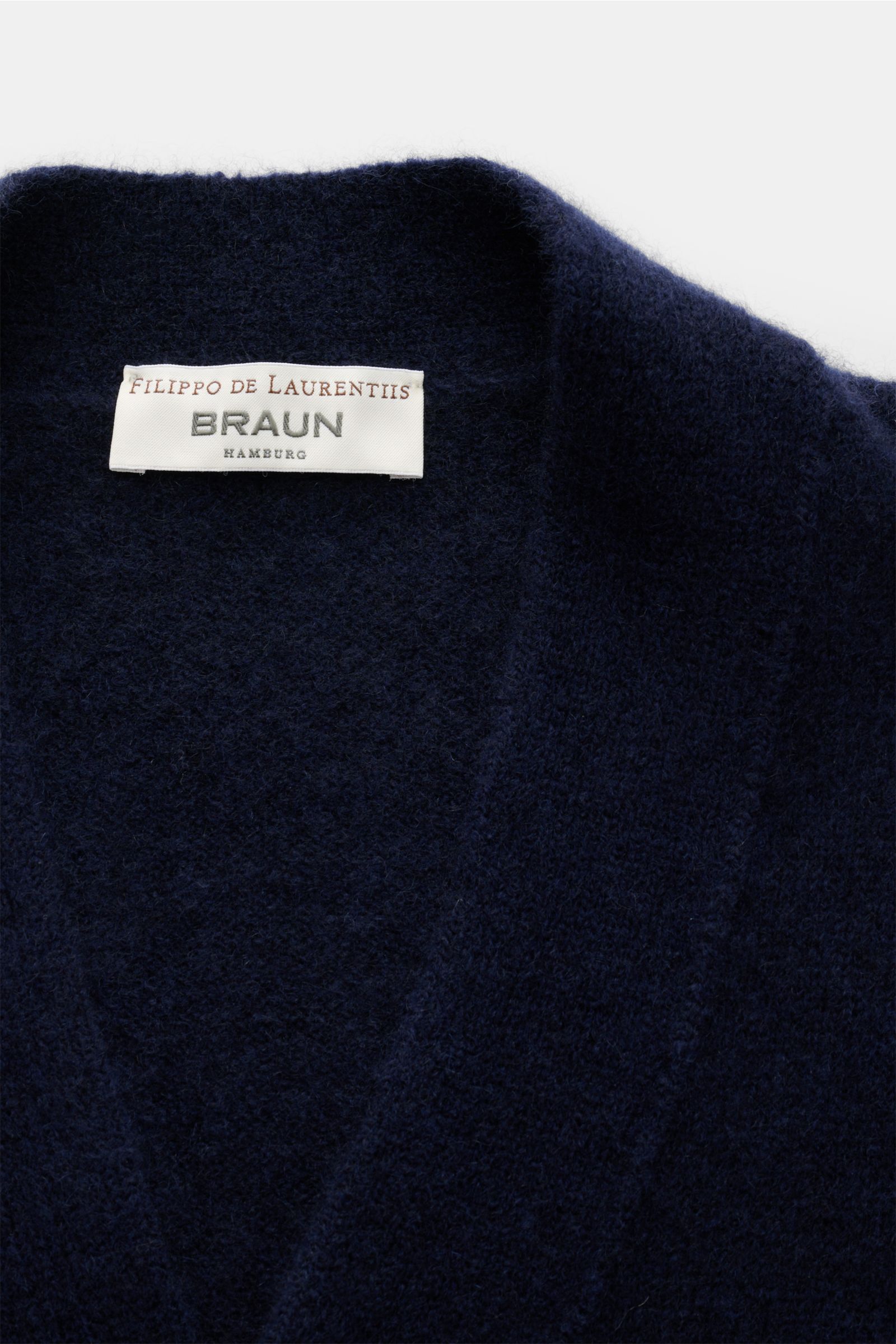 Close-up top view of the Filippo de Laurentiis Cardigan navy showing the label and soft, navy fabric texture made from a mix of cashmere, silk, and microfiber.

Description: Eine softe, luxuriöse Mischung aus Cashmere, Seide und hochwertiger Microfaser